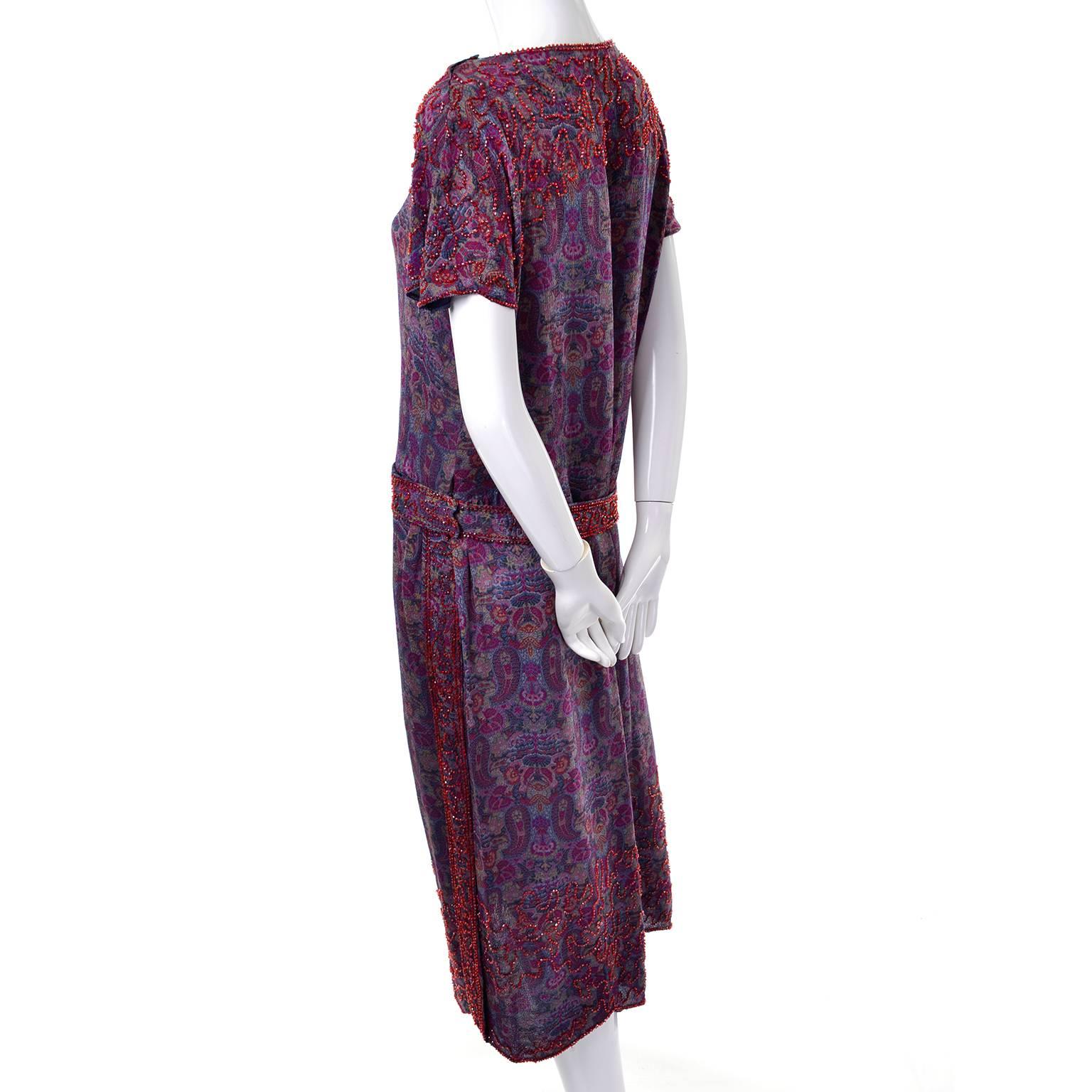 This extraordinary 1920's vintage dress is lightweight wool in blue with a magenta, green and yellow paisley print design. Small red glass beads decorate along the hem and carry on to the end of the sleeves from the bust. The sleeves and bottom hem