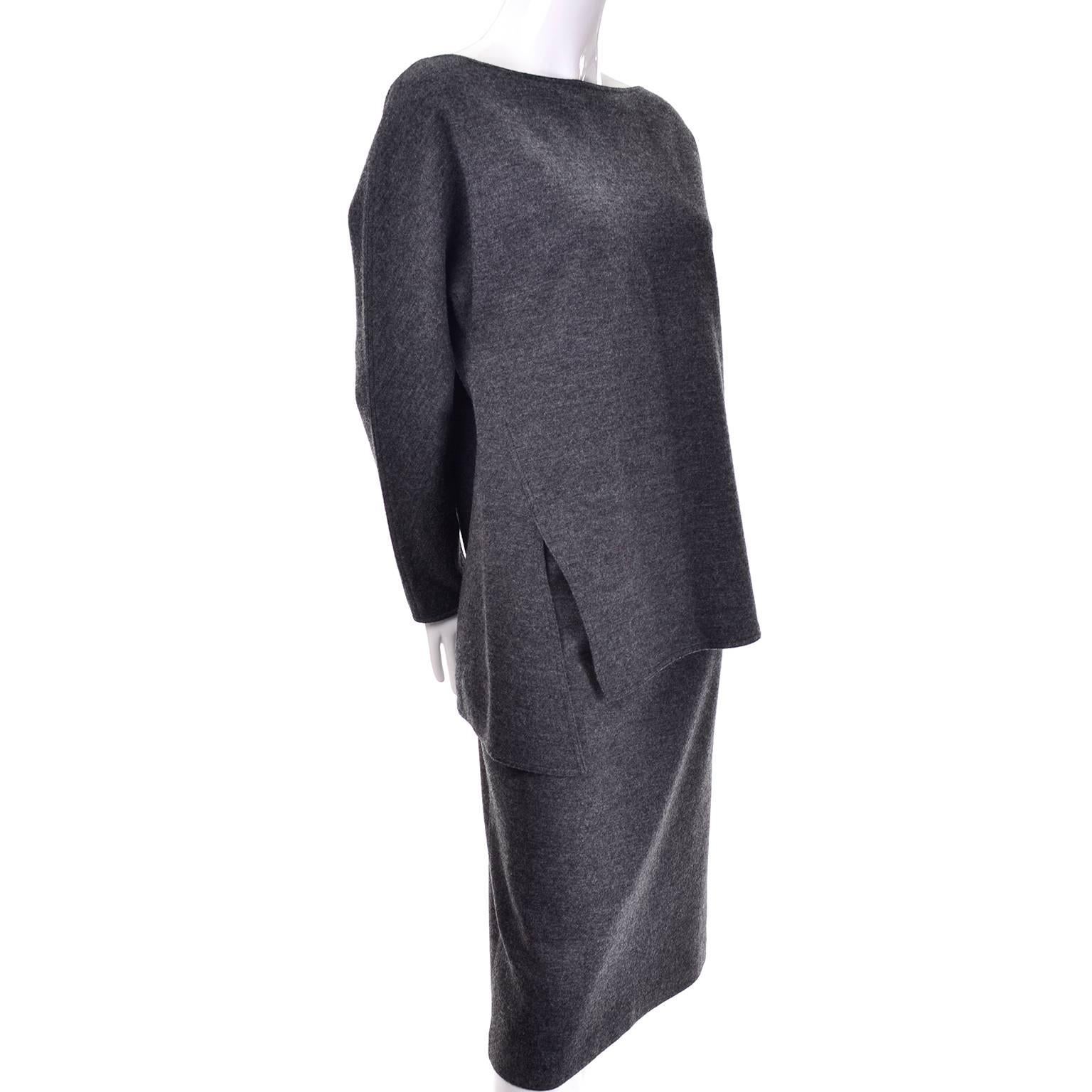 This 2 piece vintage Geoffrey Beene minimalist outfit includes a top and a skirt made of a lightweight gray wool. The skirt has a back zipper and is labeled a size 10 and is lined. The fabric has a bit of stretch to it and the outfit can be belted
