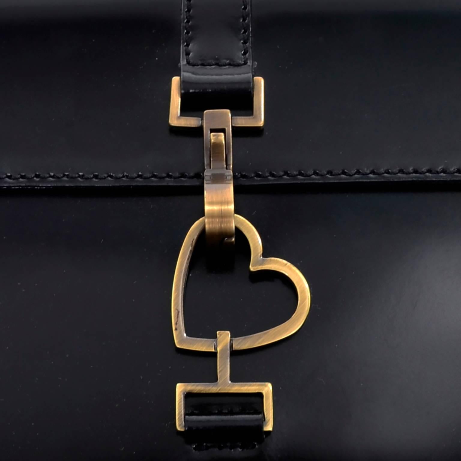 This vintage Moschino black Leather handbag has a metal heart clasp and leather strap with a 9 and 1/2
