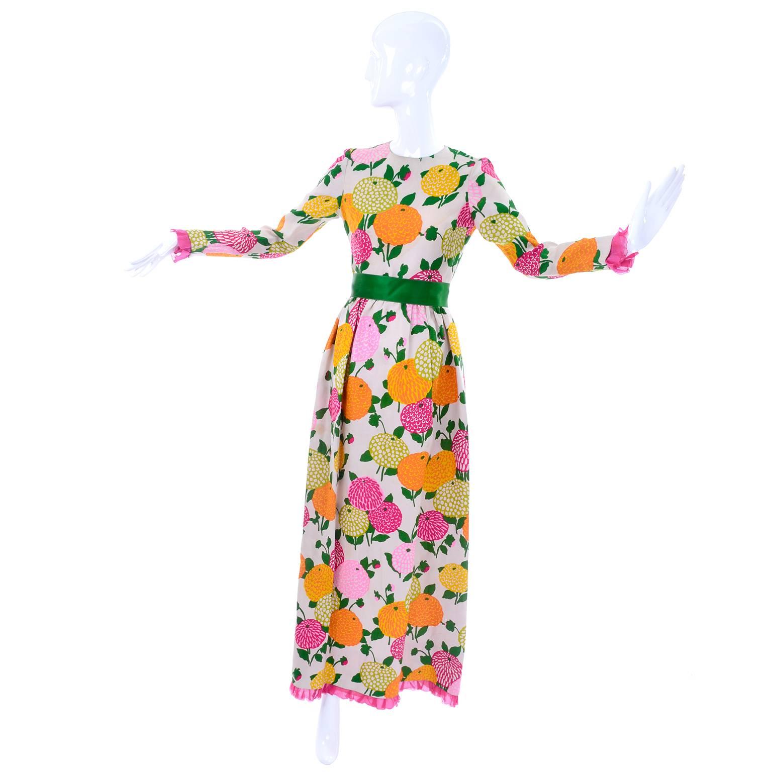 This is a beautiful, bright floral vintage silk Christian Dior numbered 24382 couture maxi dress from the 1960's. This long sleeve vintage dress is covered in stylized zinnia flowers in pink, orange, green, and yellow. The sleeves and hem both end