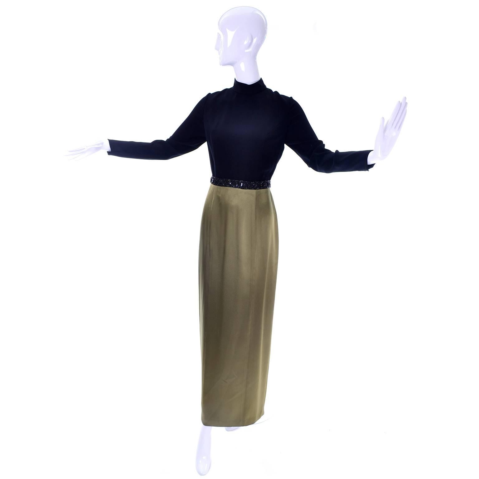 This Bob Mackie boutique vintage maxi dress has a black top and an olive green satin skirt. The waist is adorned with black beads and gemstones. There is a sensational diamond shaped open back, with layered fabric and a clasp at the high neck, and