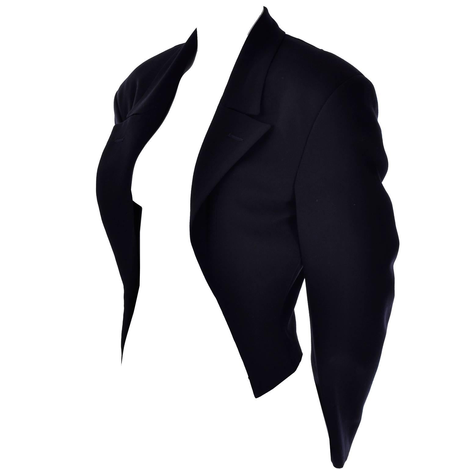 This is a Comme des Garcons cutaway jacket that is open in the front, tapering at the waist and coming to the point in front. This deep midnight navy blue blazer is cropped, with dramatic shoulder pads for a flattering fit. 100% wool jacket that is