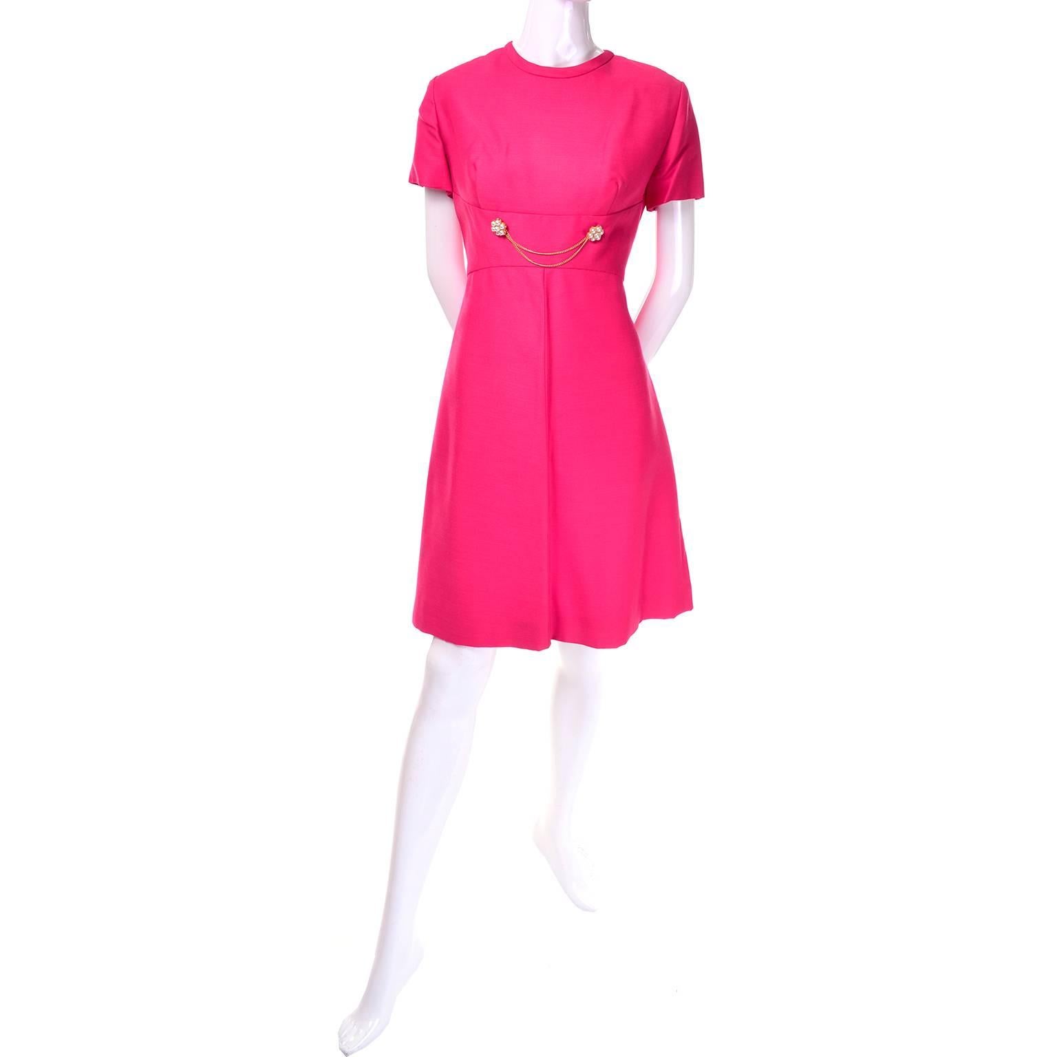 This bright pink dress and matching coat by Emma Domb is from the late 1960's but appears to have been barely if ever worn. The short sleeved dress has a fitted waist adorned with two chains and clusters of pearl beads. The coat has decorative