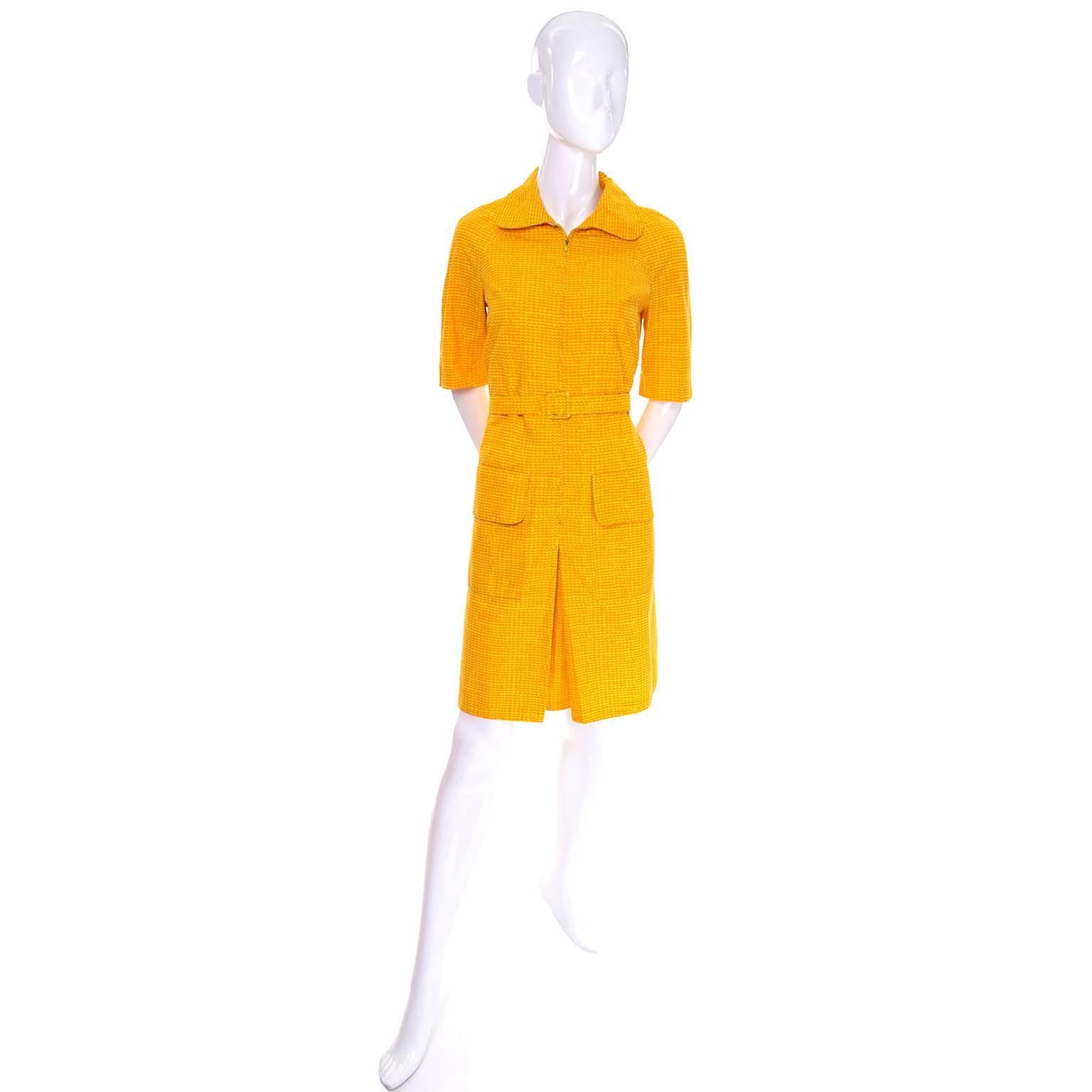 This is an adorable sun dress by Marimekko that zips down to the beginning of the central pleat in the skirt. This yellow dress has bands of orange mounds creating a pattern that almost looks like waves. It has two flap pockets at the hip and short