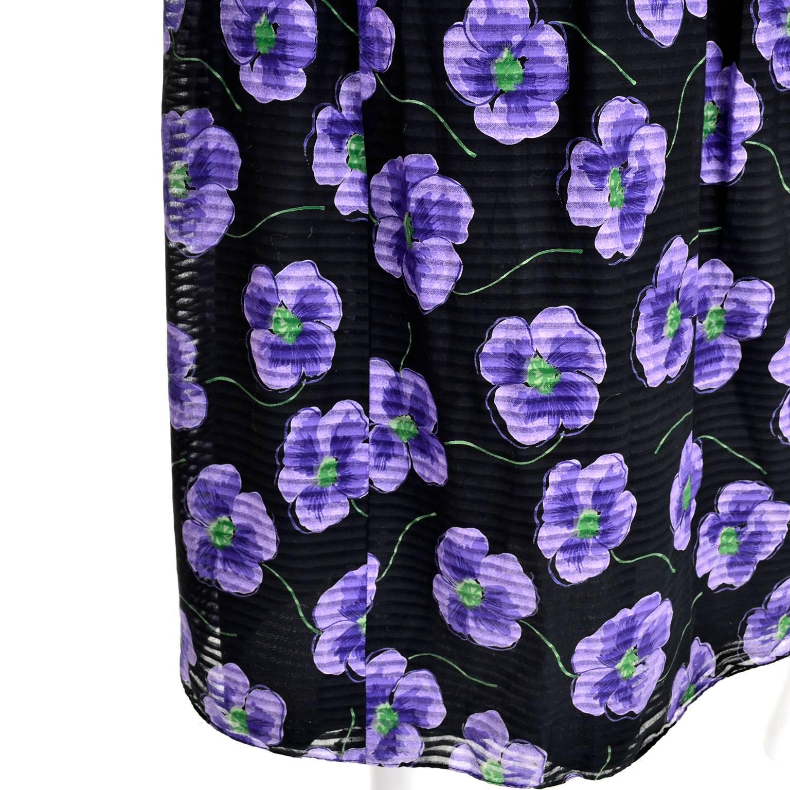 This is a pretty black Anthony Muto vintage dress adorned with beautiful purple flowers. The summer cotton or cotton blend voile dress has a sheer, subtly striped outer layer, and is lined in black fabric. It is sleeveless with a scoop neck and