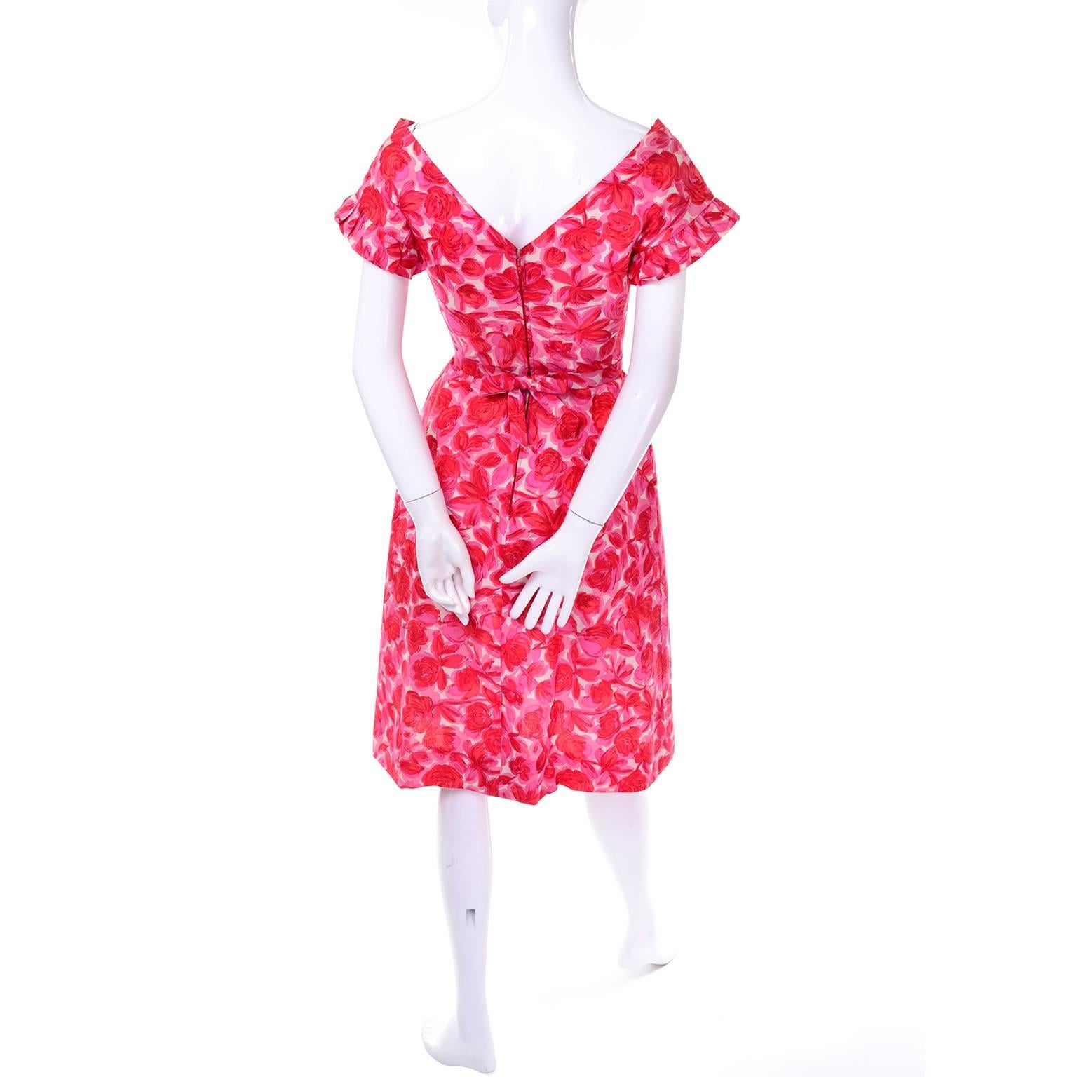 This pretty vintage pink floral silk dress has no label but is exquisitely designed and very well made. The bodice has a faux pinafore look with pretty pleats and there is an attached fabric sash that snaps closed with a bow in the back. The dress