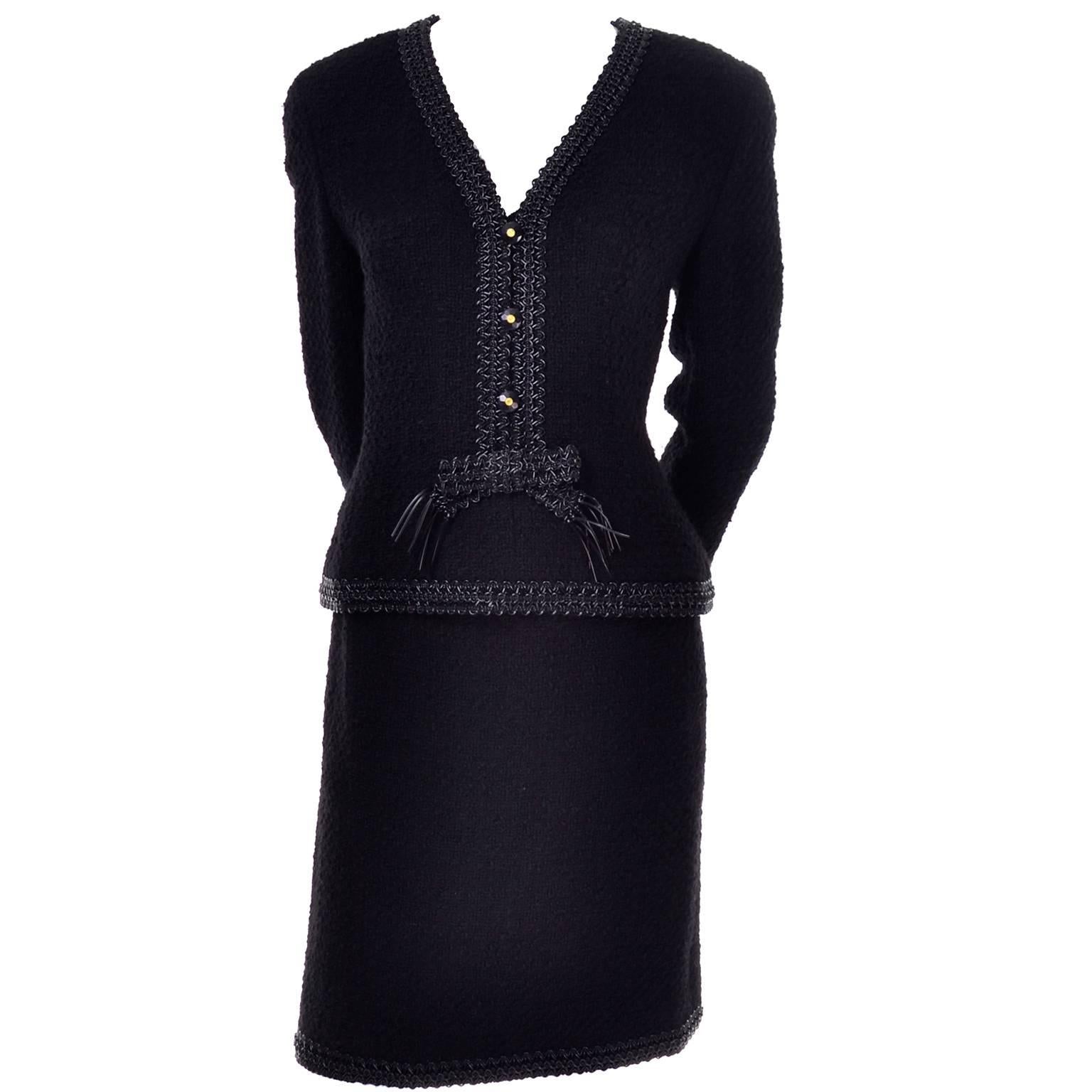 This beautiful black wool boucle Chanel suit is from Fall Winter 1994. The suit has a straight skirt and semi peplum style jacket. The jacket has decorative CC logo buttons up the front and closes with a back zipper. Both pieces have beautiful black