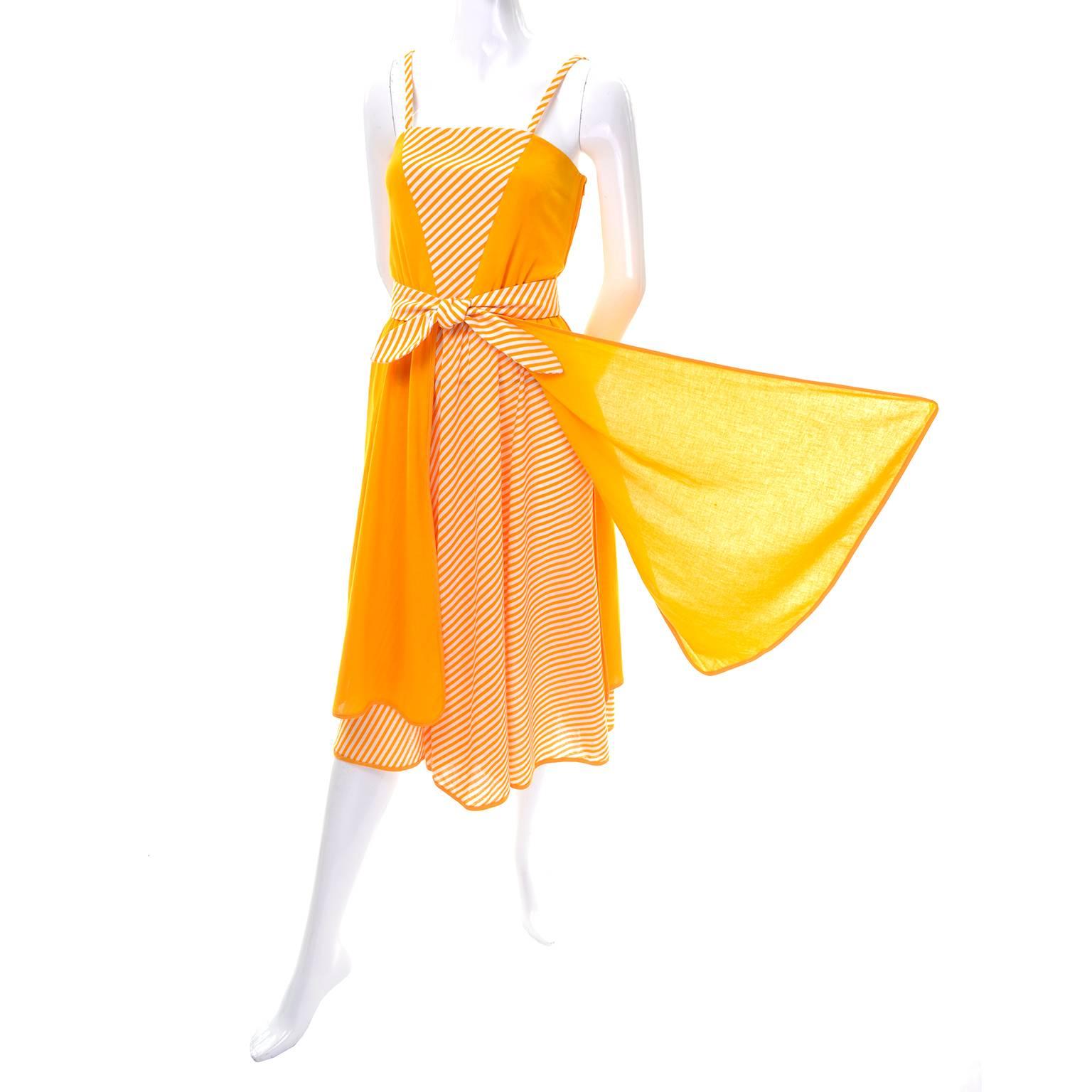 Cette robe solaire vintage des années 1970 de Lanvin a des bretelles spaghetti et des bandes orange/jaune et blanches sur la jupe et en forme de V sur le buste. La jupe à rayures est composée de quatre panneaux fluides uniques qui s'attachent à la