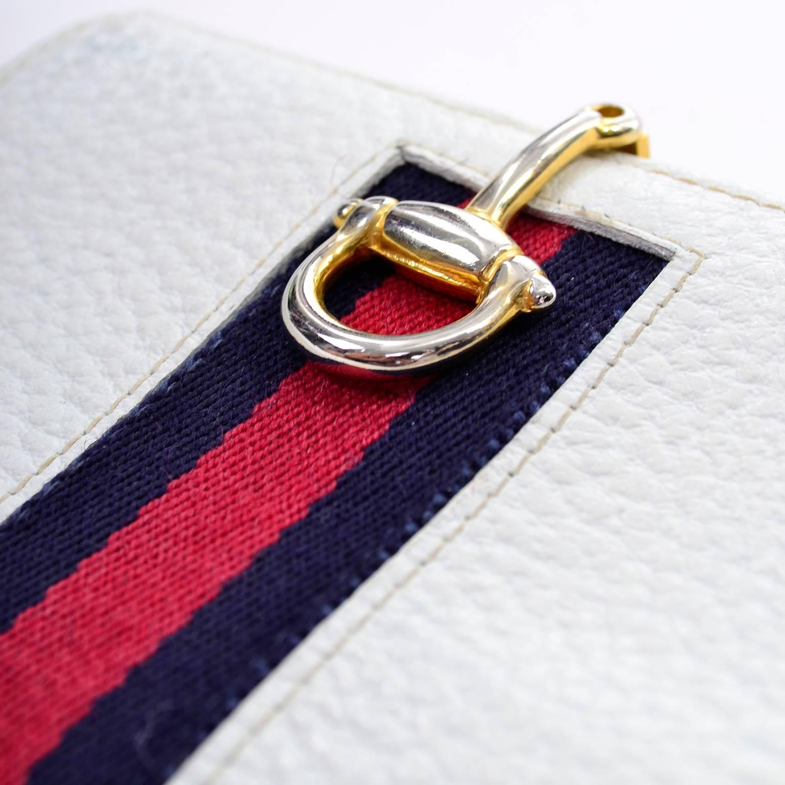 This white leather gucci wallet has gold hardware and blue and red striped trim.  The wallet measures 4 and 5/8 inches by 3 and 5/8 inches and has 2 sections and 4 inside flap pockets.  The wallet measures 7 inches when open flat.  A beautiful