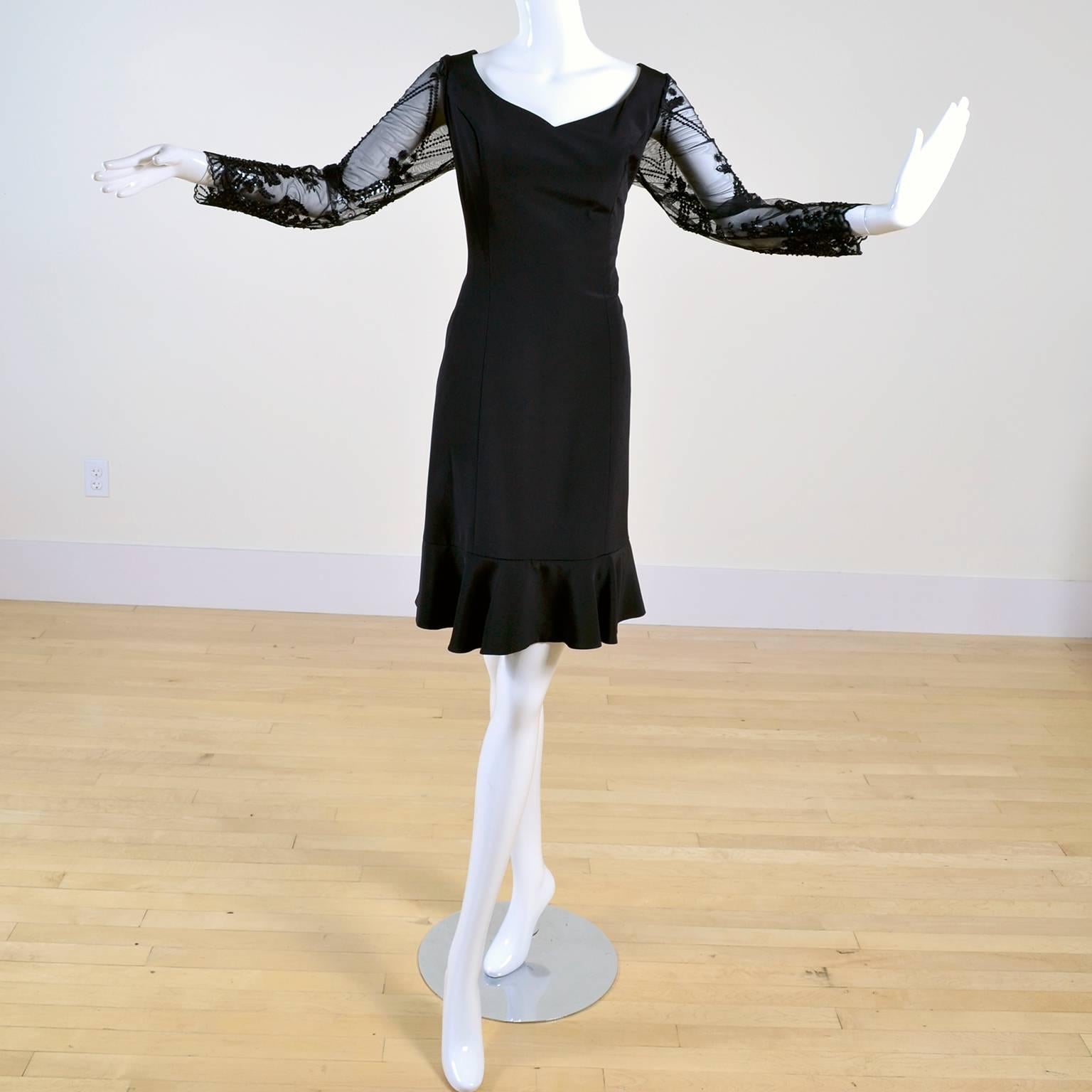 This is a beautiful vintage Escada black silk dress with beautifully embroidered net sleeves that are embellished with beading and sequins. The dress has a ruffled flounce hemline and zips up the back and was designed by Margaretha Ley.  The dress