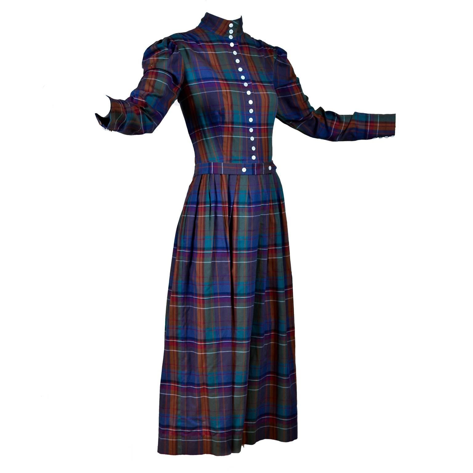 This is a rare 1980's Ralph Lauren vintage plaid dress with a high neck and white buttons down the front. The fabric of this vintage dress is a gorgeous plaid in shades of orange, red, purple and green, with a matching fabric belt that buttons