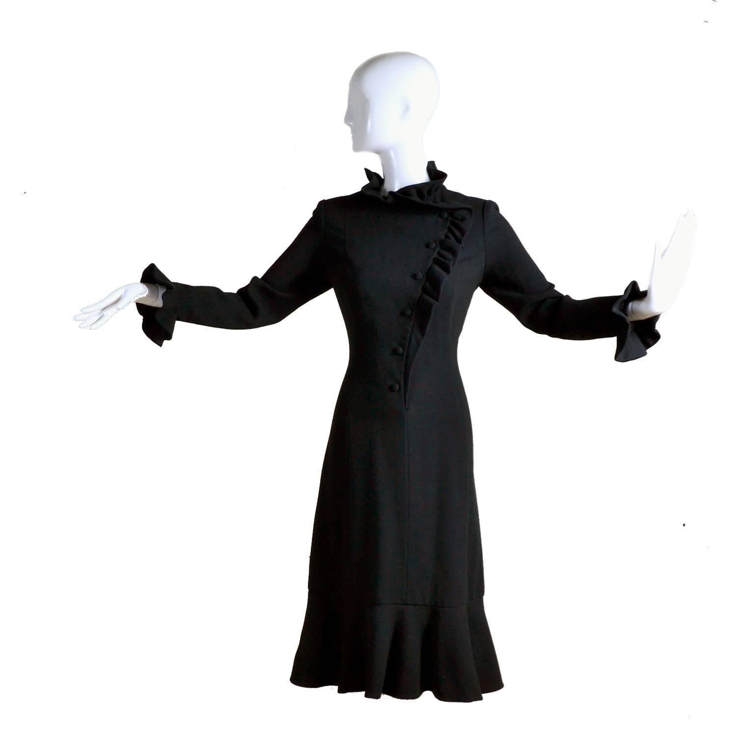 This 1970's vintage black crepe wool dress was designed by Jean Louis Berthault who was once a costume designer  at Columbia  and later, Universal Pictures.  The dress has a ruffled collar, ruffled hem, ruffles on the cuffs, and asymmetrical ruffle
