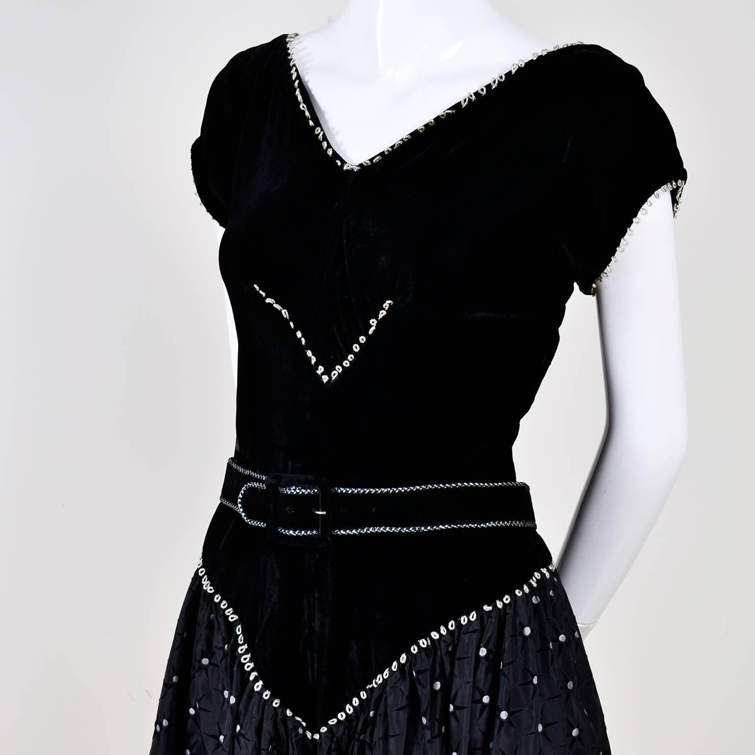 Gorgeous vintage 50's dress with a black velvet bodice that ends in a low V past the hips. The drop waistline, neckline and short sleeve openings are lined with silver loops. The bodice also has a small V of silver loops in the center, just below