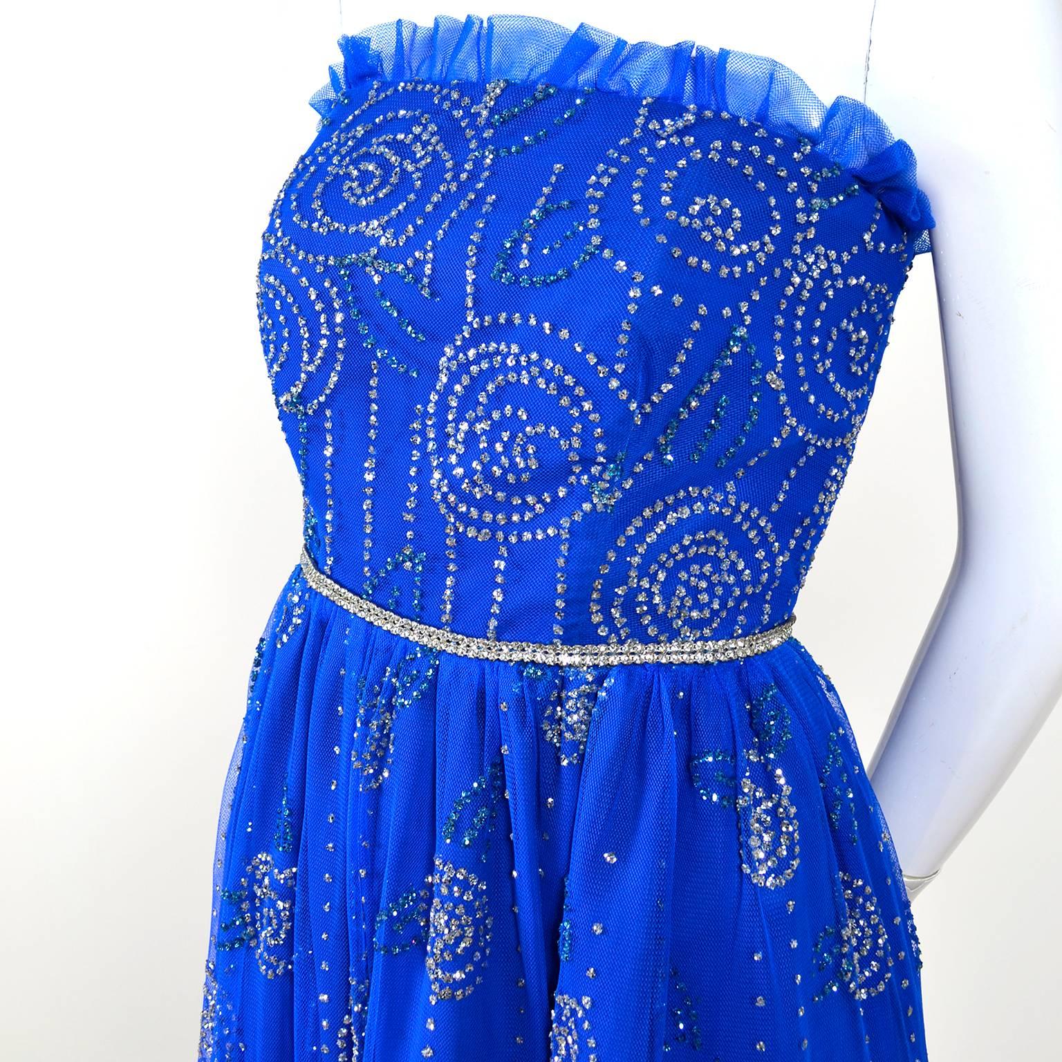 This vintage early 1970's party dress is in a bright blue tulle over satin.  This strapless dress has gorgeous designs throughout created with rhinestones.  We estimate the dress to fit a modern day size 2.  The dress closes with a back zipper but