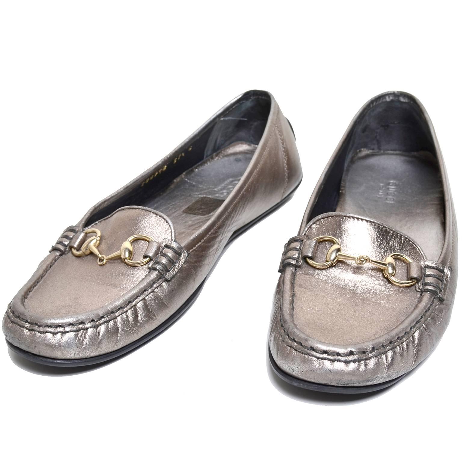 These are adorable metallic slip on loafers by Gucci. These drivers are metallic silver, with a slight gold cast. They have silver hardware across the upper, with the classic Gucci horse bit buckles. The soles are rubber, coming up on the heel with