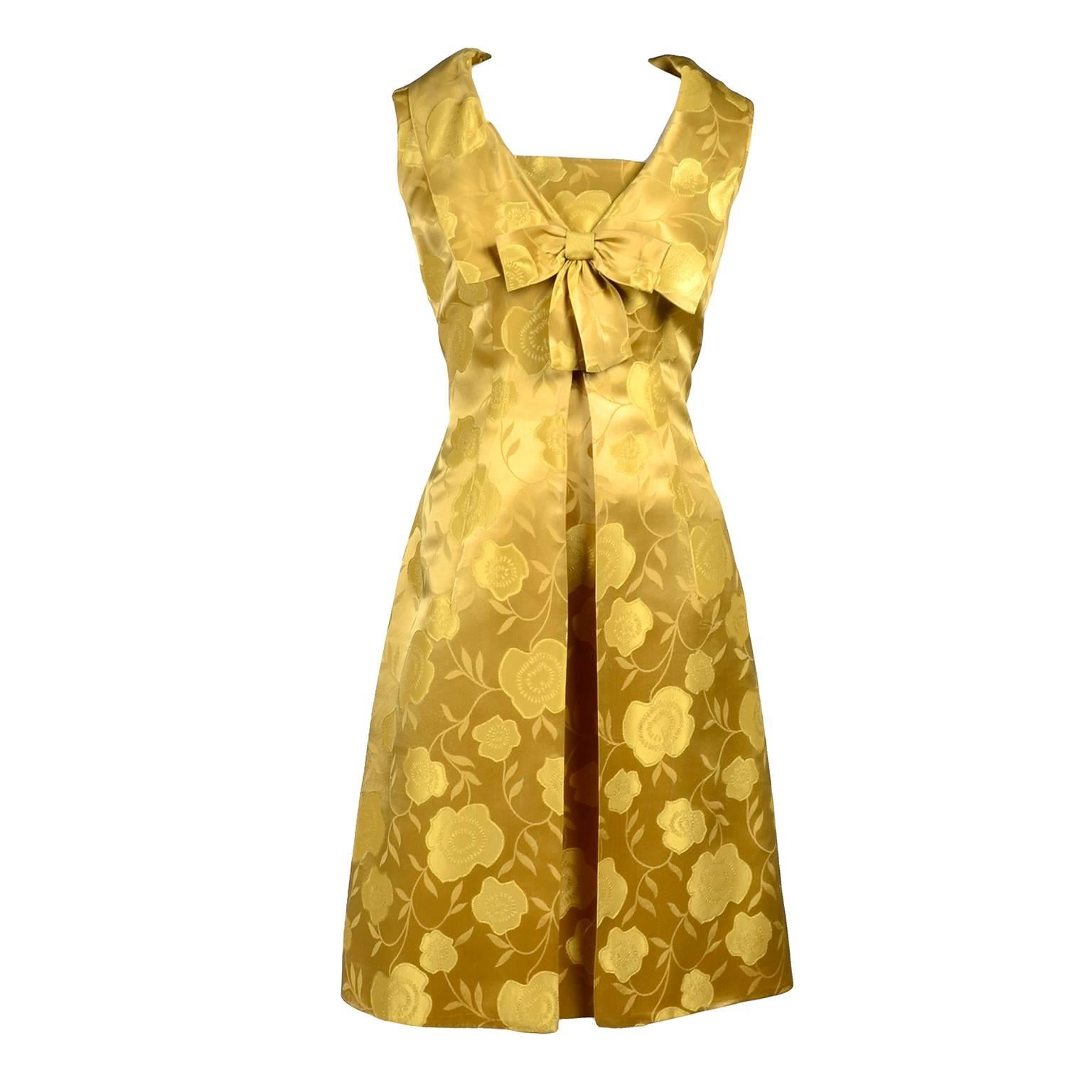 This is a pretty gold floral satin 2 piece vintage cocktail dress ensemble that includes a spaghetti strap dress with a matching sleeveless long jacket. The jacket or sleeveless overdress secures with a snap and hook and eye at the bust under the