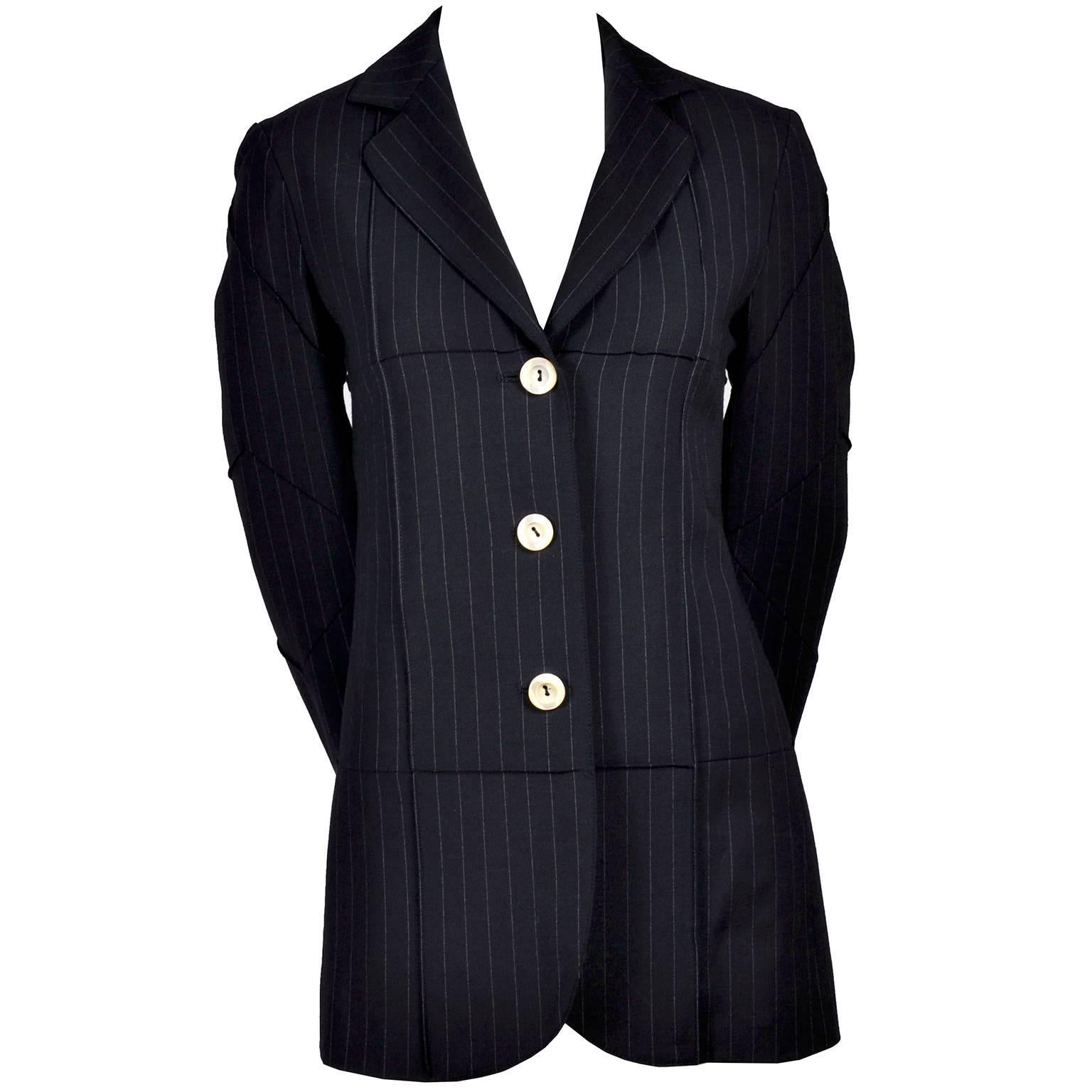 This Moschino Cheap & Chic blazer jacket was made in Italy and is in a midnight blue wool blend with thin, light blue vertical pinstripes. This wonderful blazer has interesting chevron seams along the arms, and vertical and horizontal seams across