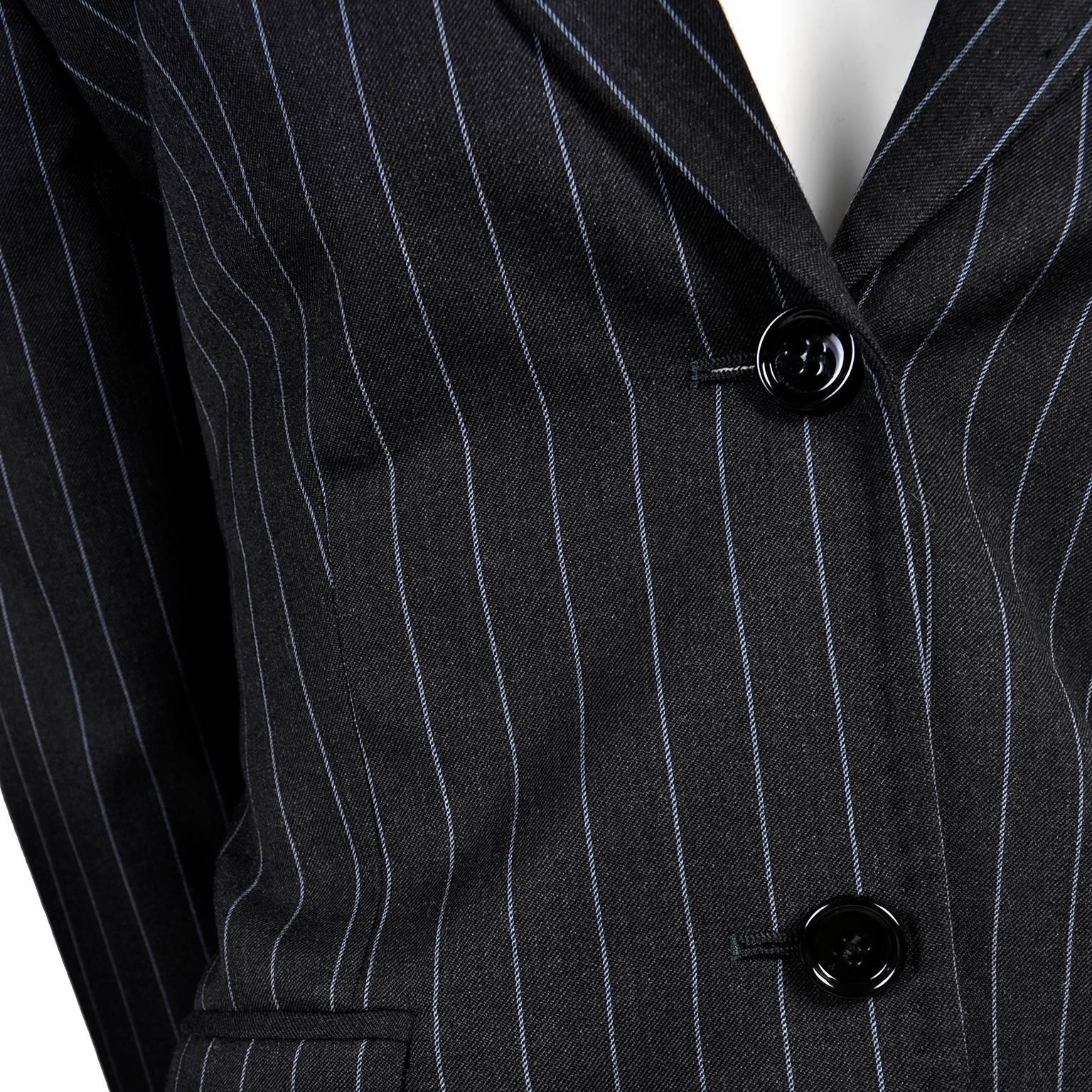 This is a gorgeous pantsuit from Dolce and Gabbana made of 100% virgin wool. It is a beautiful dark charcoal gray/black, with light blue pinstripes running vertically. This women's suit has a two button blazer and matching trouser pants. The jacket