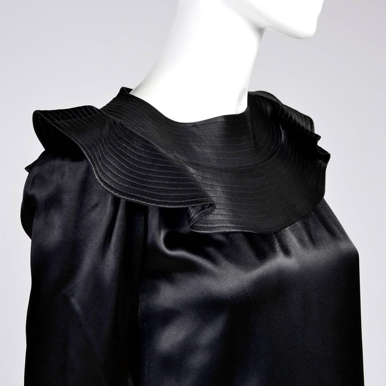 Cette magnifique robe vintage a été conçue par Albert Nipon dans les années 1970. La robe est en satin noir avec un col à volants qui présente des rangées de surpiqûres. Cette robe est tellement belle qu'elle n'est pas aussi belle sur les photos