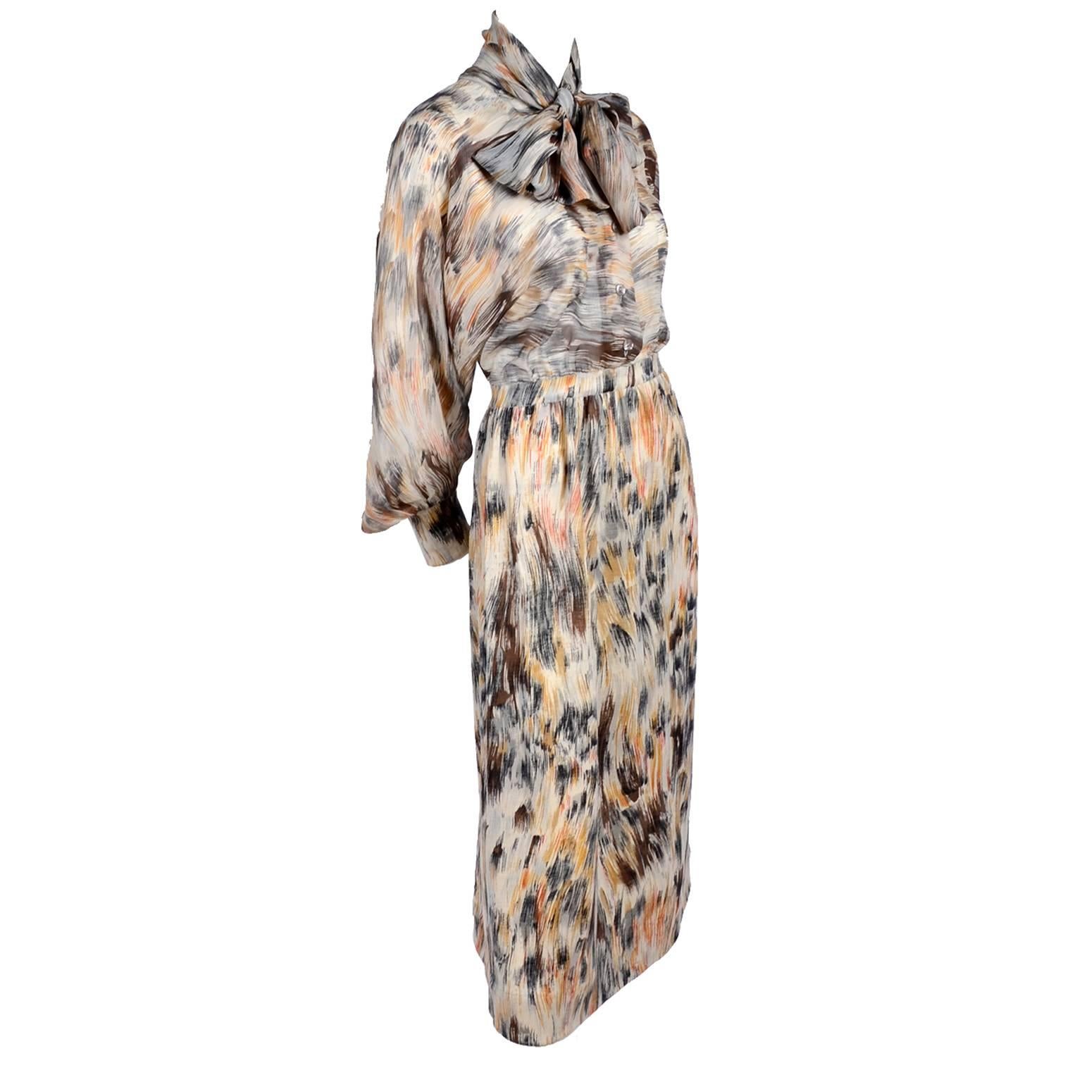 This is an incredible vintage Goldworm dress with a beautiful sheer silk bodice, wool cuffs, and a wool skirt.  The abstract print is in shades of brown, copper, and gray. There is an attached scarf to the bodice and beautiful dolman sleeves. This