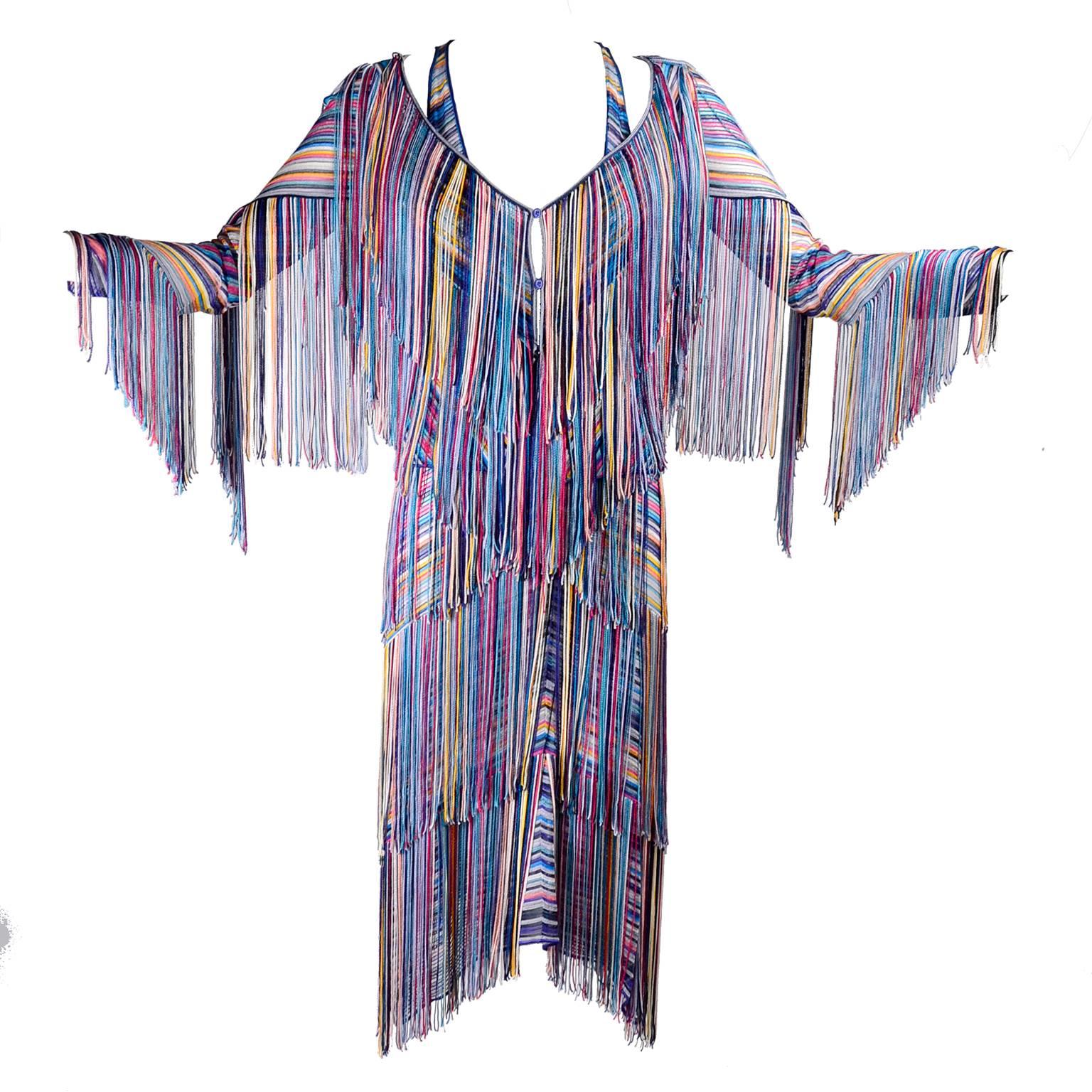 This multi colored woven slip dress has strands of tiered fringe in the same color as the dress in rows down the front.  This dress slips overhead and has a deep V in the front. This dress has a slight stretch and comes with a sweater or jacket in