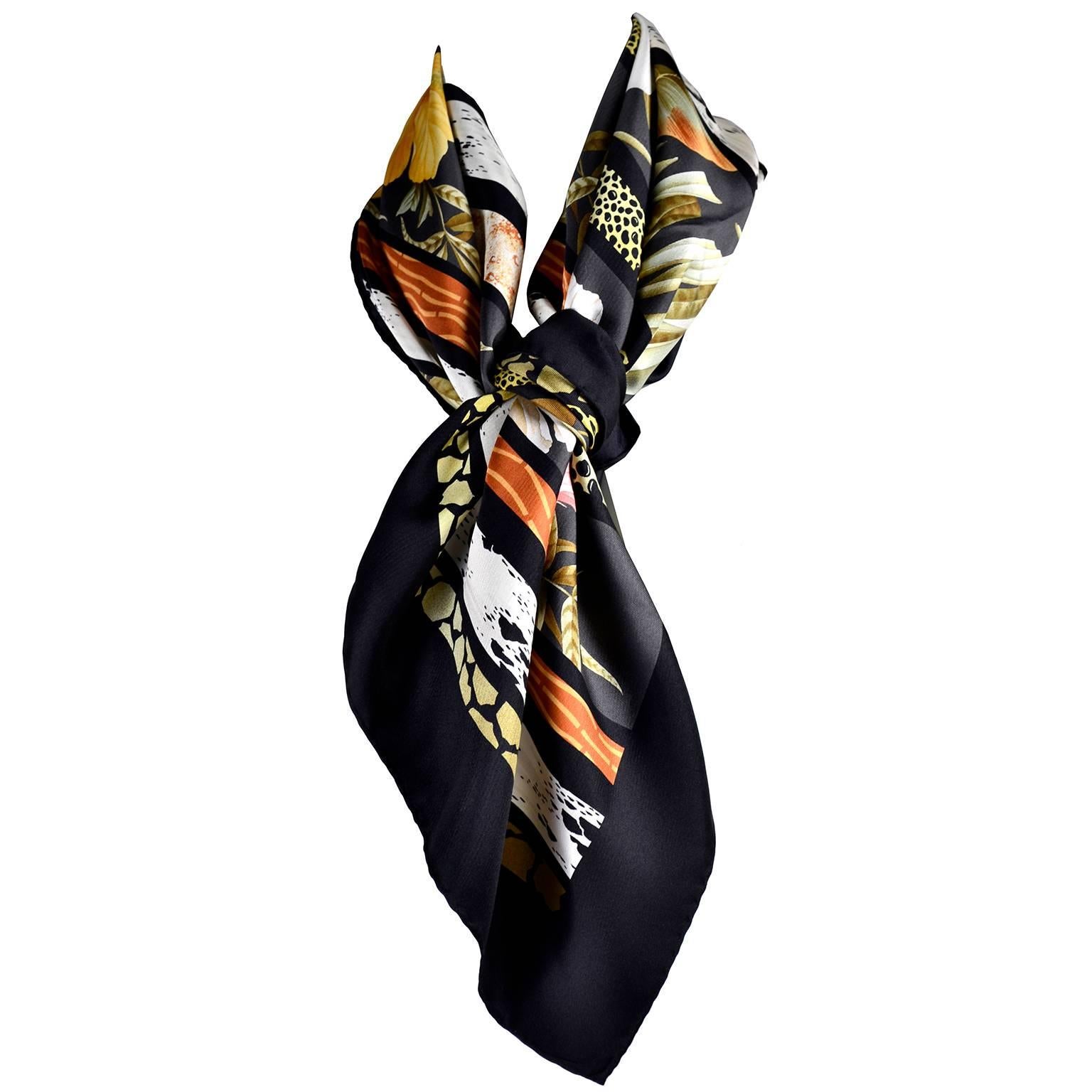Il s'agit d'un magnifique foulard vintage en soie de Salvatore Ferragamo, de couleur noire avec des bandes d'imprimés animaliers et des fleurs d'hibiscus jaunes et roses, des lys de calla et des feuilles vertes.  Cette magnifique écharpe vintage en