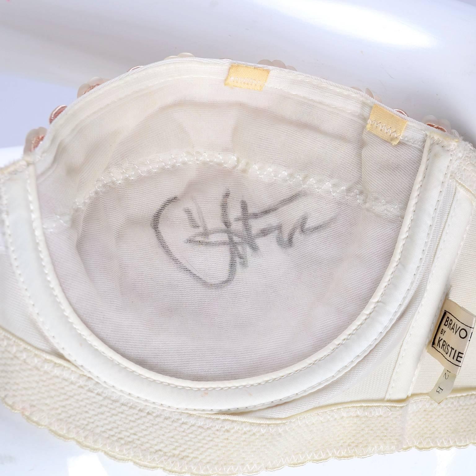 This strapless bra came from a Cher memorabilia collection that we acquired from a collector.  The bra is signed by Cher inside of the cup and the label reads: Bravo! by Kristie. The bra is cream with pink soutache trim, pink sequins, and pink
