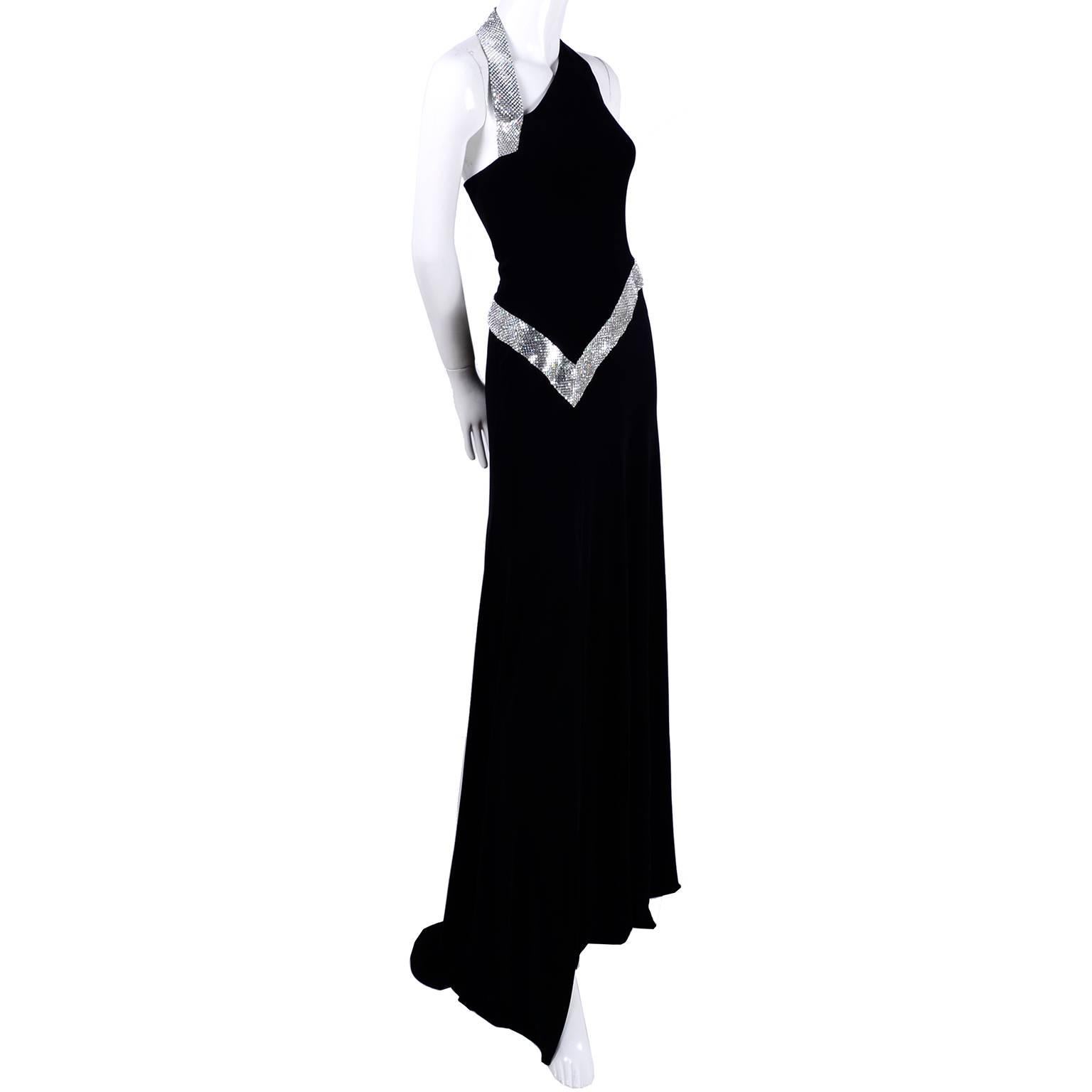 This is a show stopping vintage dress from Jiki of Monte Carlo that was made in France in the 1990's. The dress is black crepe with a thigh high slit and is trimmed with absolutely gorgeous silver mesh alternated with crystal clear rhinestones. We