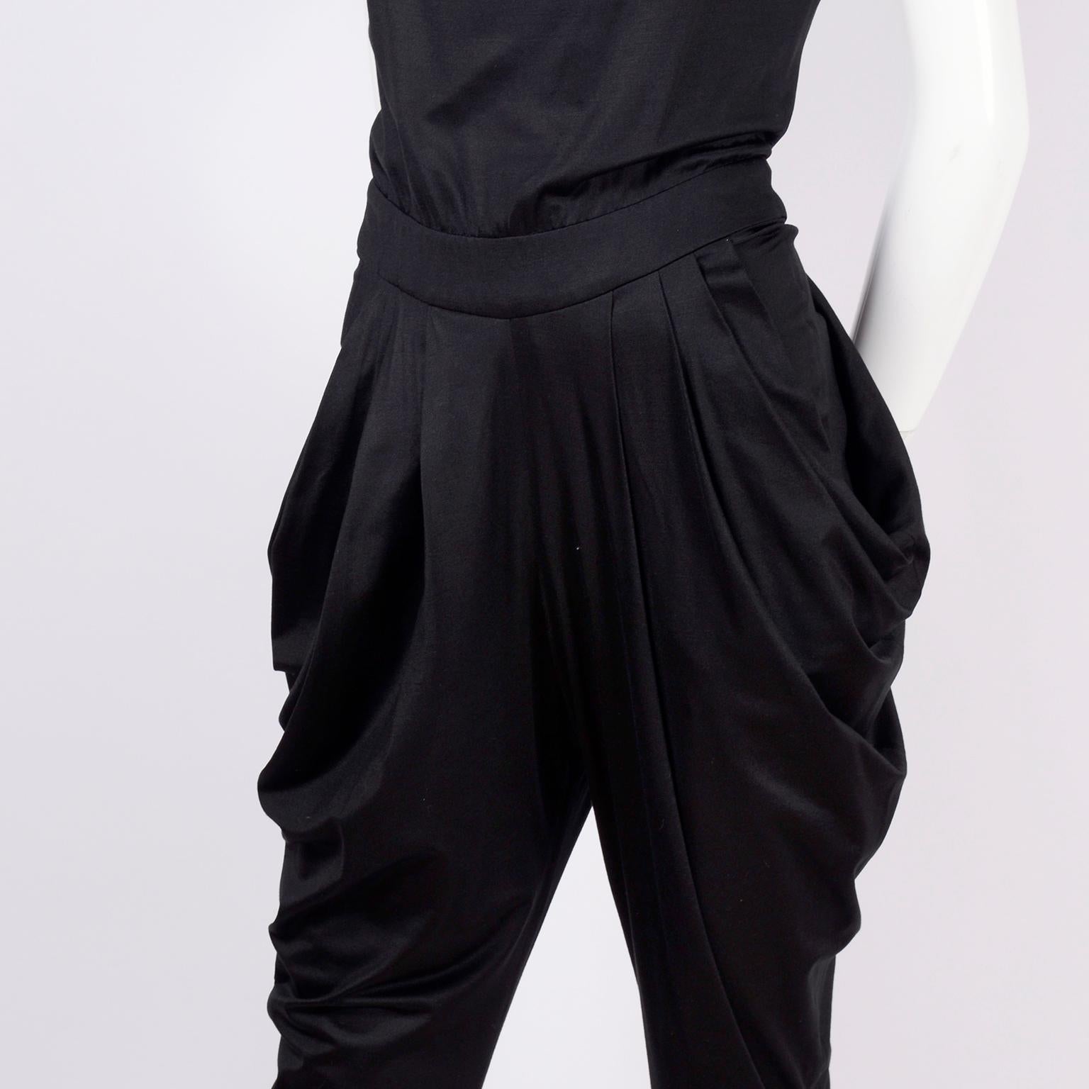 This is a fabulous vintage 1980's black harem style  jumpsuit. This super chic jumpsuit is sleeveless, and zips up the back to the waist, with three buttons above that. The long straps make the bodice create a nice gathering, and the pants have
