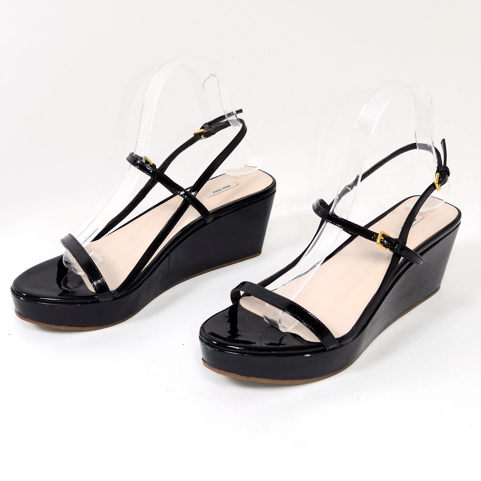 This is a great pair of strappy Miu Miu sandals with two buckling straps, one across the top of the foot and one behind the heel. There is another thin black strap that goes across the toes. This is a black patent leather platform shoe with a wedge