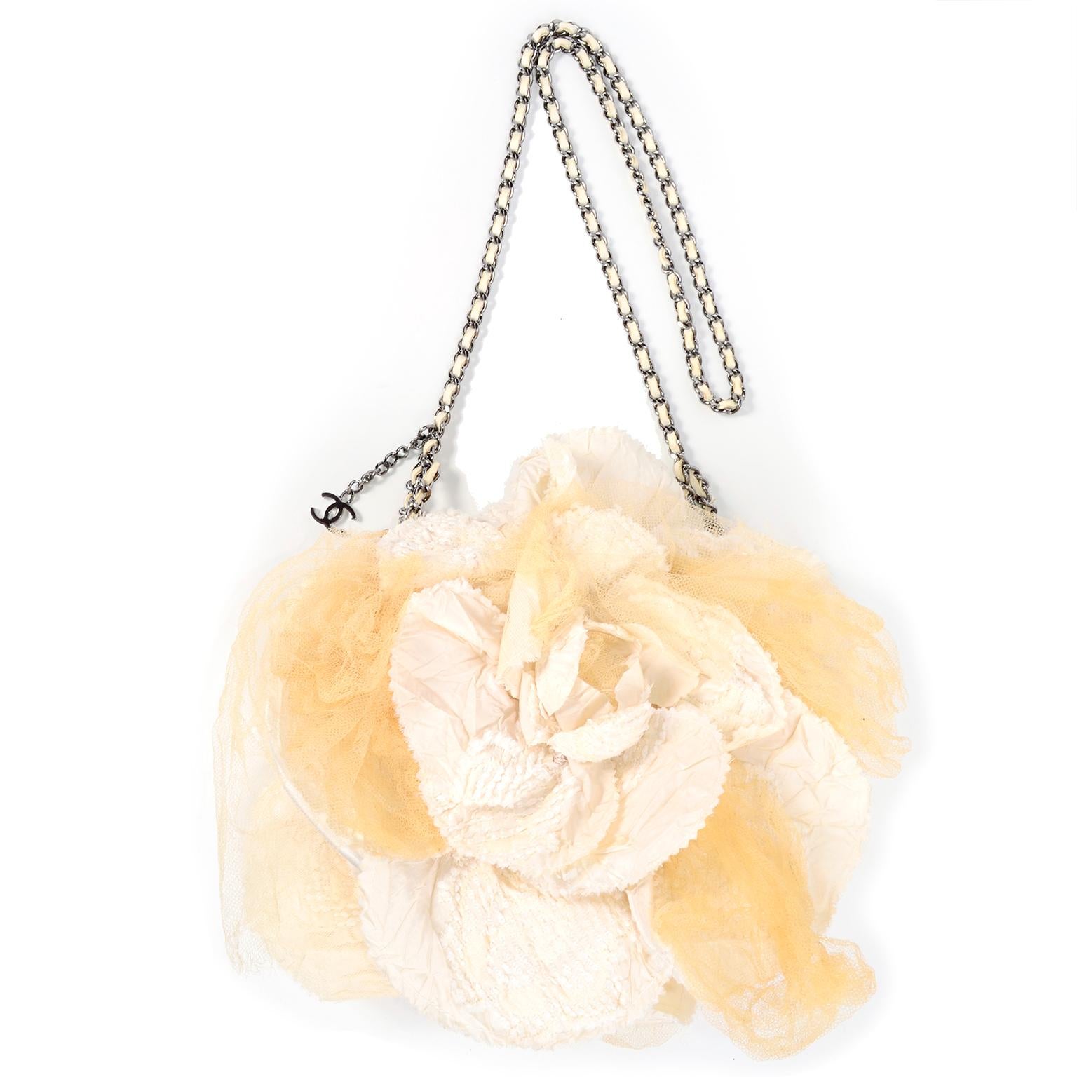 This is a beautiful Chanel cream silk handbag with a darker cream netting or tulle that forms a camellia flower on front and back. The netting is intentionally frayed at the ends and the bag closes with a snap on the  top and has a silver tone metal