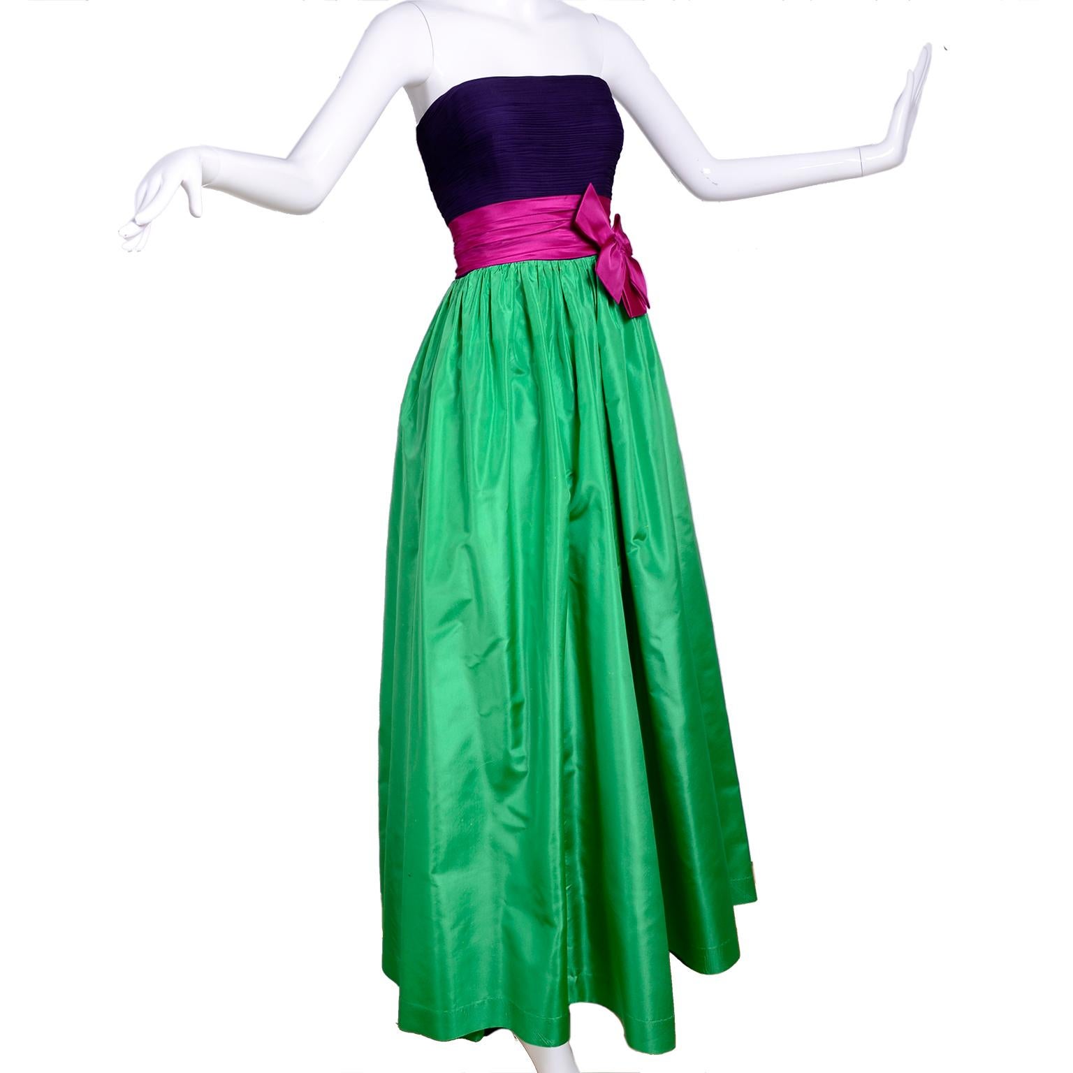 This is a beautiful Nina Ricci strapless evening gown with a ruched deep purple silk strapless bodice. The skirt is fully lined and there is a pink satin belt with an attached bow at the waist. This is a lovely vintage dress that would be perfect