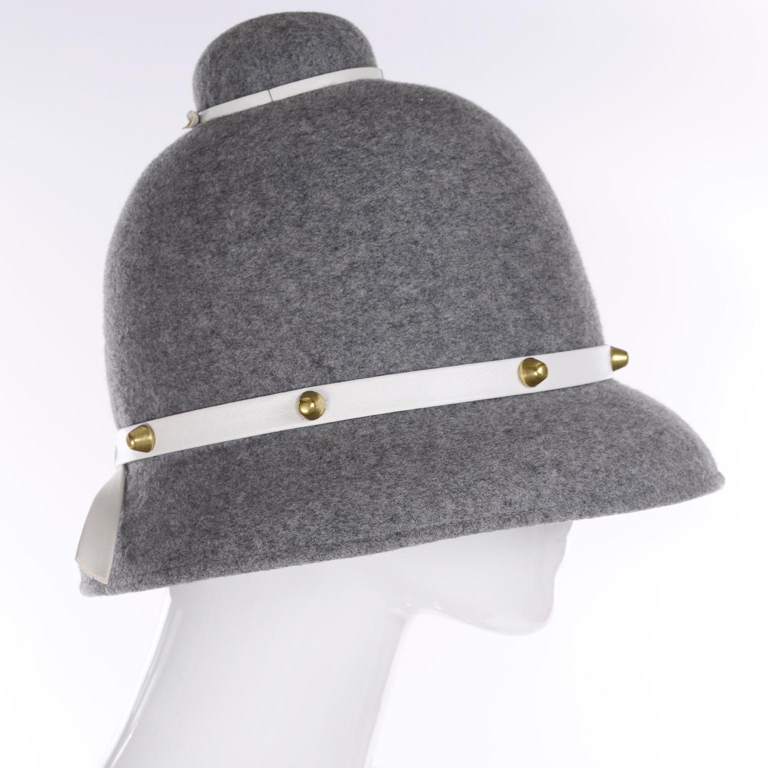 This is a wonderful vintage Mr. John Classic hat in gray wool with leather trim studded with brass.  We love Mr. John hats and this one is a perfect example of the style they brought to millinery in the mid century. This hat measures 22