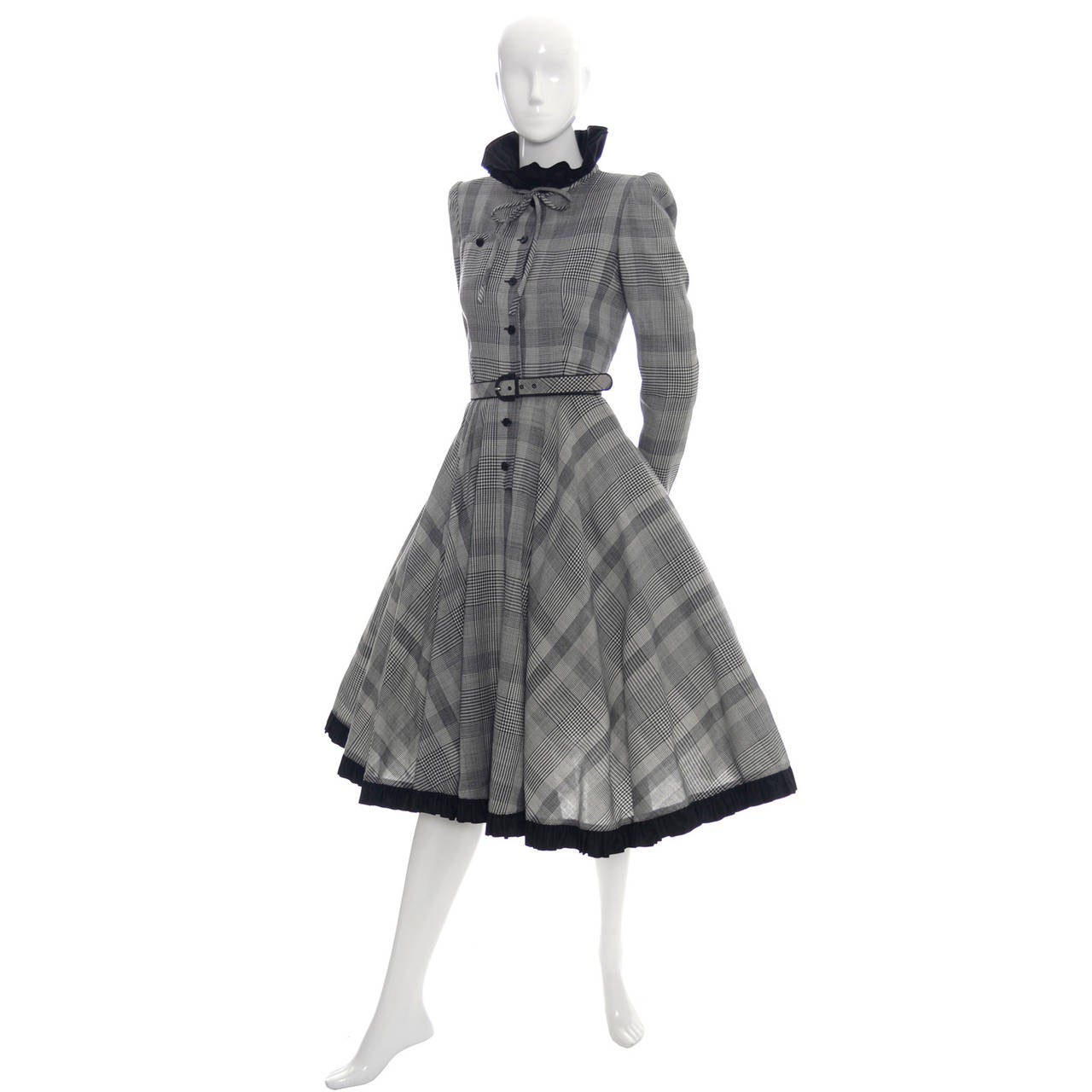 This is a vintage Valentino Boutique hounds tooth plaid wool dress from the  very early 1980's. The dress is in excellent condition, has its original belt and black satin trim at the hemline, cuffs and collar. The dress buttons up the front and also
