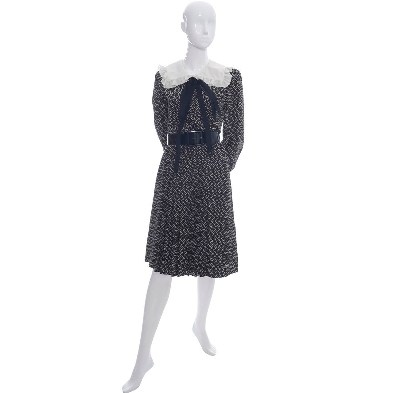 This vintage dress is from the Yves Saint Laurent Rive Gauche collection and was made in the late 1970's.  The dress is black with creamy pale ecru dots and has a white ruffled collar. There is black trim on the cuffs and a black silk tie under the