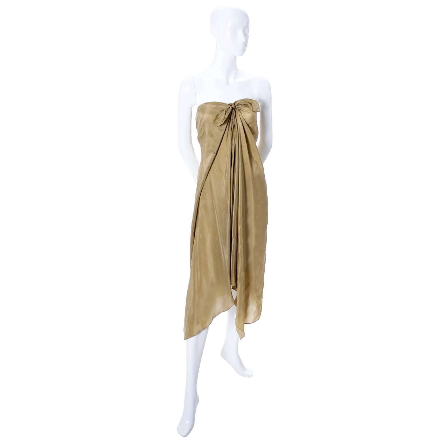 This pretty dress is new with its original tag and was designed by Ralph Lauren. The dress has the purple Ralph Lauren Collection label and is marked a size Medium.  This is a soft gold silk sarong or toga style dress that falls below the knee at