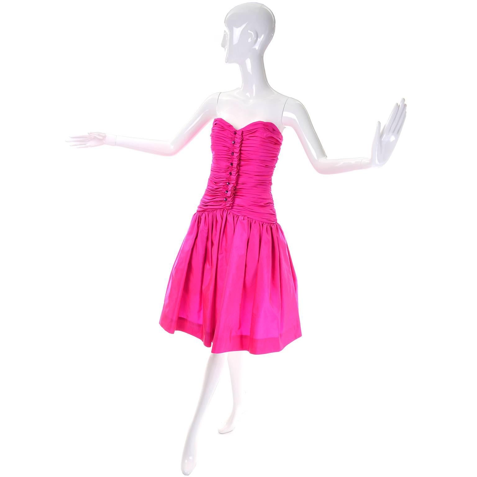 This is a show stopping vintage Victor Costa hot pink strapless dress with a rouched bodice and drop waist. Faceted faux gemstone glass buttons run up the front. There is a short crinoline under skirt and an even shorter tulle piece on top of that