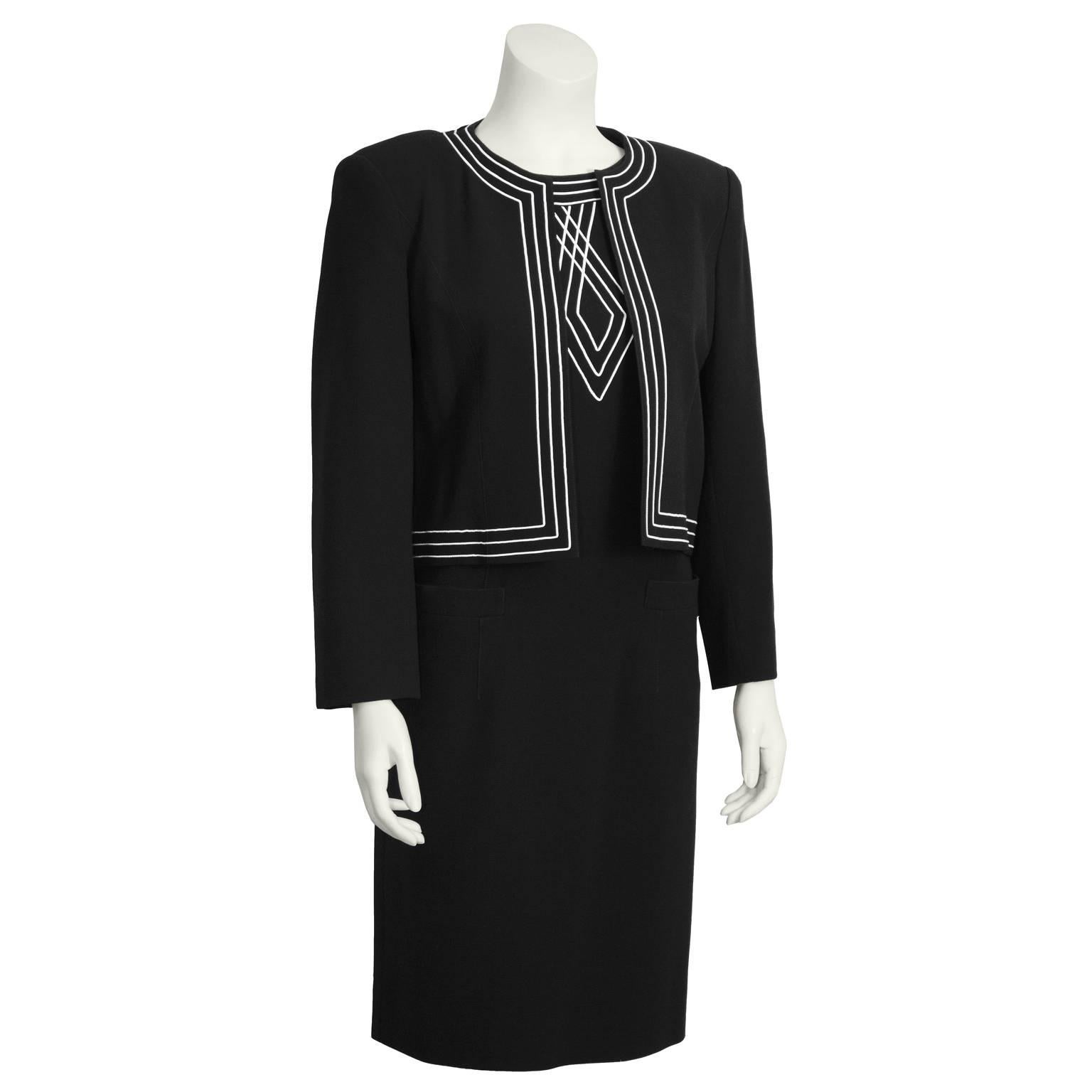 Sophisticated and elegant 1970's Louis Feraud black dress and jacket duo with white embroidery. Sleeveless sheath dress has two patch pockets and a back zip closure. Cropped jacket has embroidered trim and design on the back. Excellent vintage