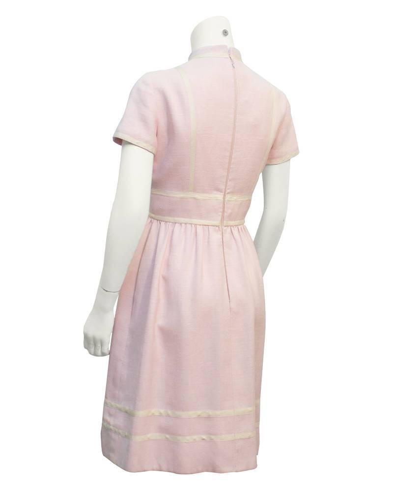 Geoffrey Beene baby pink linen day dress from the 1960's. This sweet dress has white piping along all edges and is finished with two buttons at the waist. Zipper up the back. Slight gather to the fullish skirt, classic Beene lady like details. In