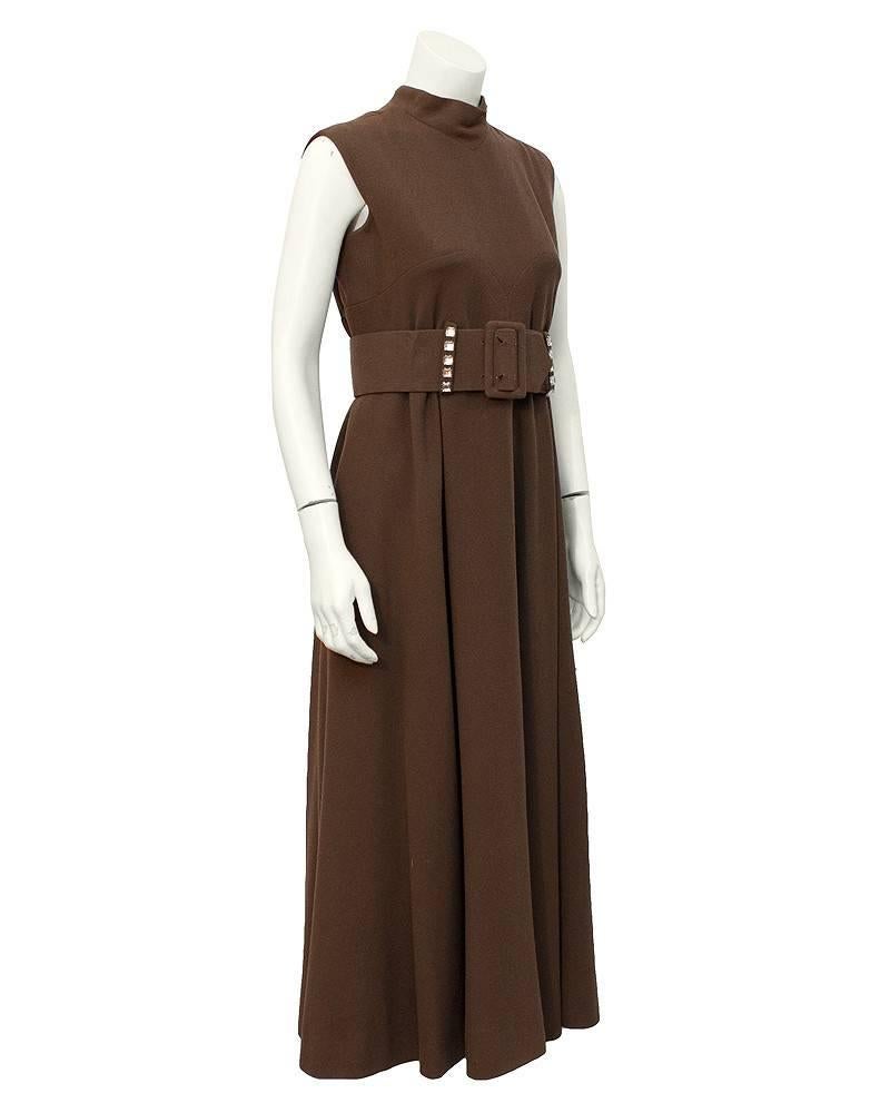 Chic daydress from Pauline Trigere circa 1970. The brown wool crepe maxi dress is sleeveless with a raised collar and a wide belt that sits at the natural waist. The belt features square rhinestones applied to the belt loops and a large two prong