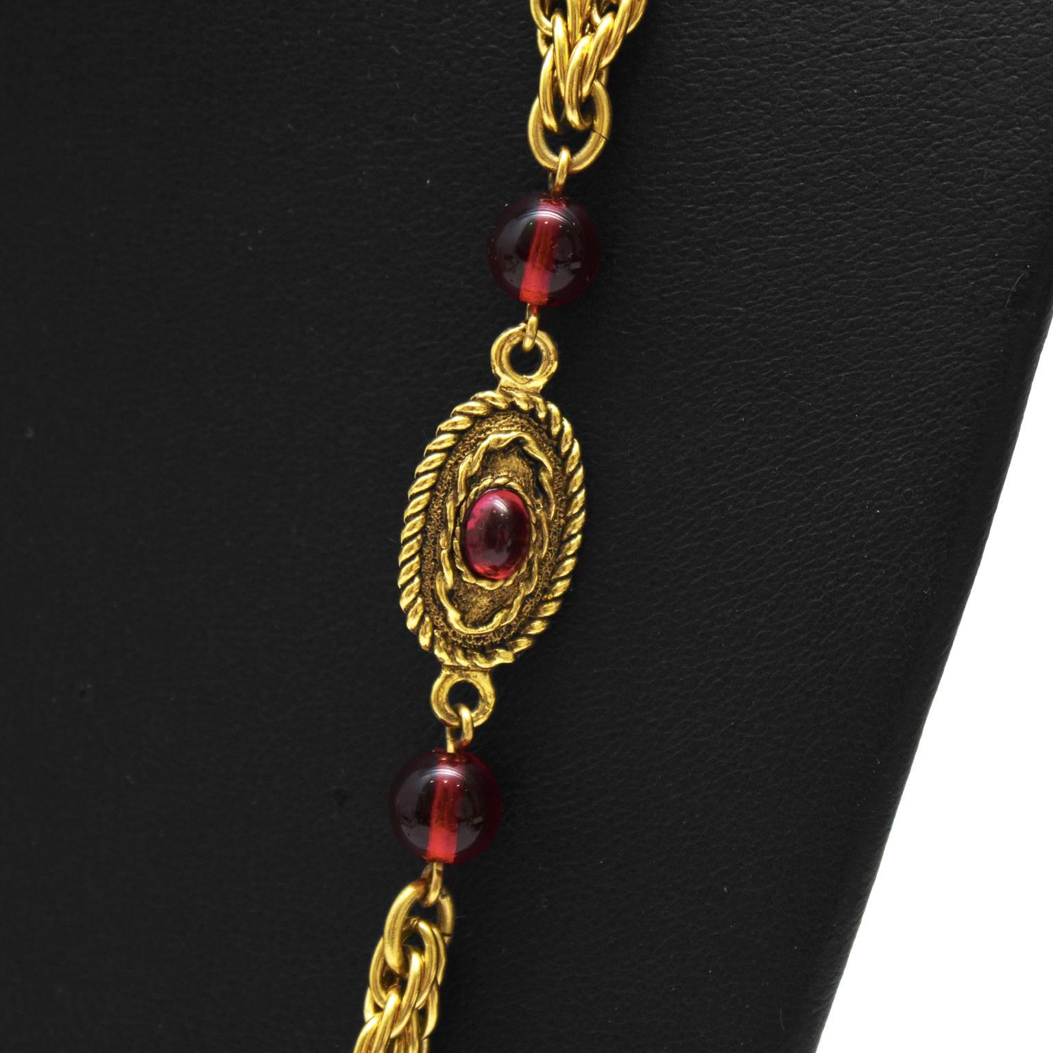 Early edition Chanel double rope chain long necklace with red glass bead detail from 1982. The double rope chains connect red poured glass beads and oval shaped charms with matching poured glass at the center surrounded with a twisted rope detail.