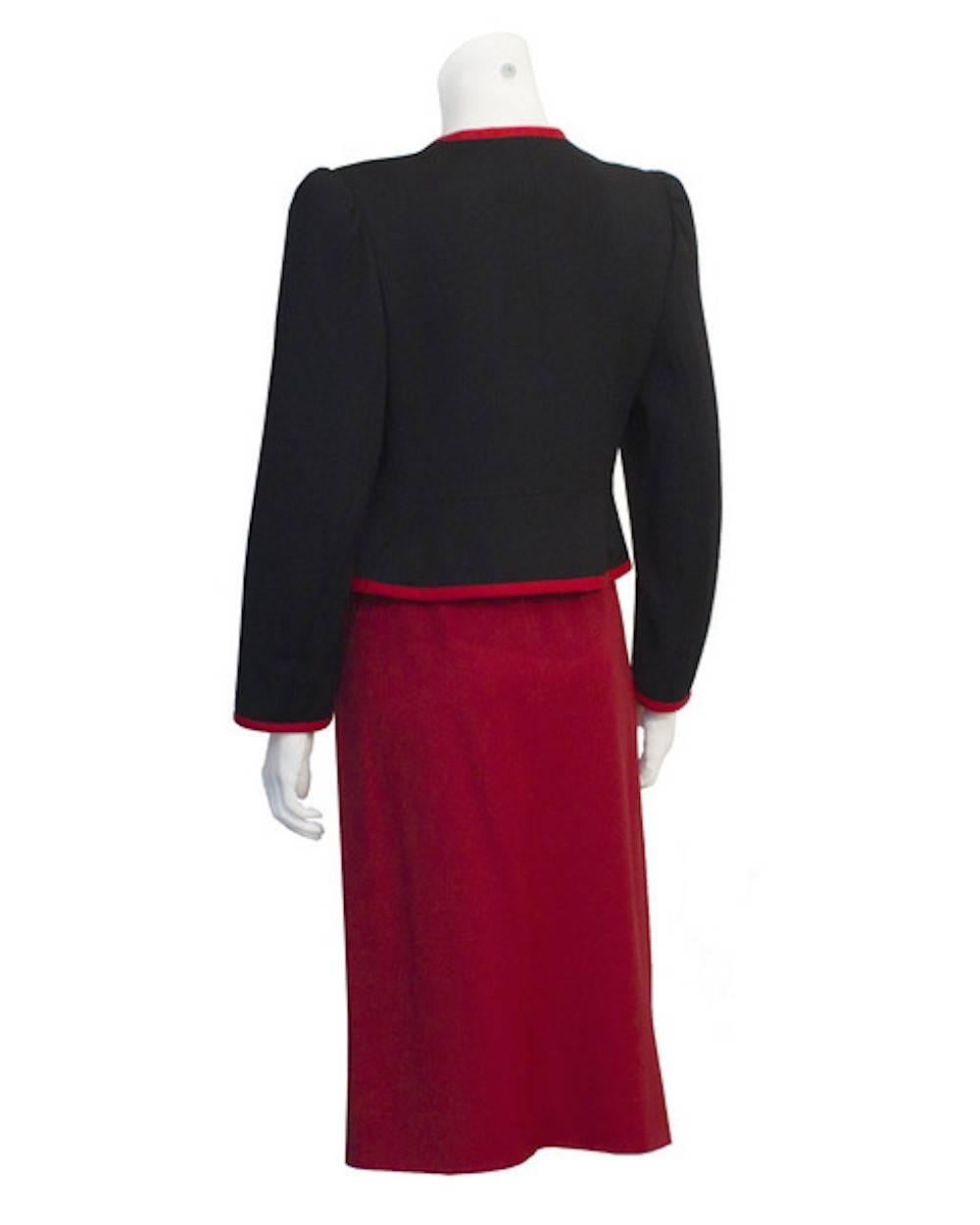Very simple yet chic Yves Saint Laurent red and black couture label suit from the 1980s. The black wool gabardine jacket with red piping and buttons is the perfect piece to be worn with jeans or over another skirt but looks amazing when paired with