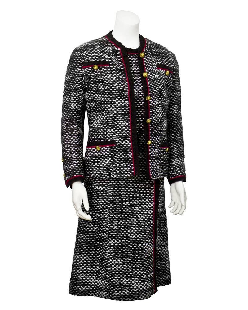 Exquisite 1970's haute couture black and white boucle short sleeve dress with fuchsia trim complimented with a classically tailored Chanel jacket with lions head buttons, patch pockets and matching fuchsia trim. In addition there is a matching full