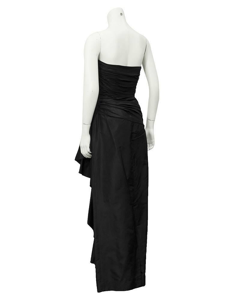 A fabulous 1980's Vicky Tiel black strapless gown. 100% silk and purchased at Bergdorf Goodman. The bodice is ruched and crosses over on the front. The ruching gets wider across the hips creating a draped effect over the lower stomach. The