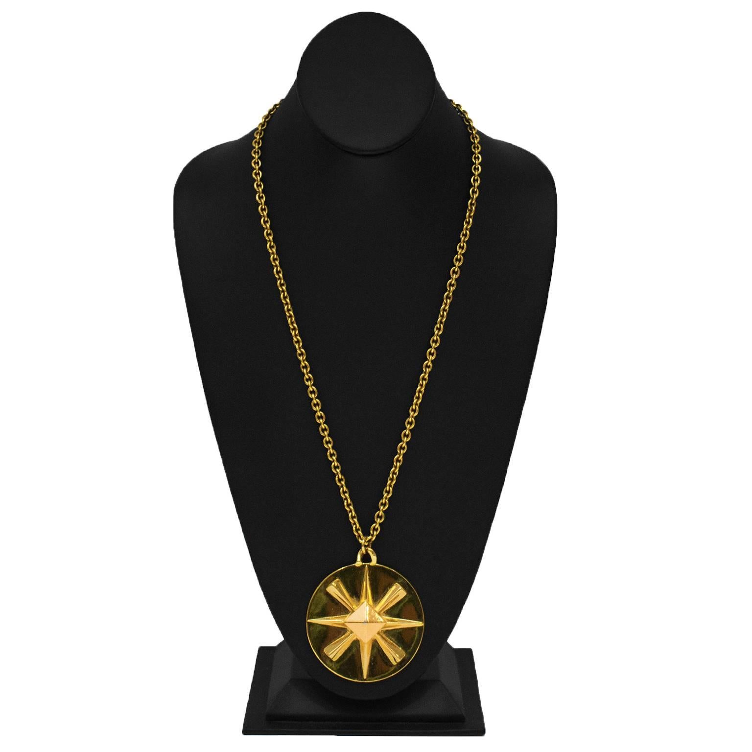 Pendentif surdimensionné en pierre dorée de Chanel sur une longue chaîne en câble d'or. Le pendentif rond est orné d'un logo CC d'un côté et d'une étoile de l'autre. Il se ferme par un fermoir à ressort circulaire. Etiquette ovale de Chanel sur la