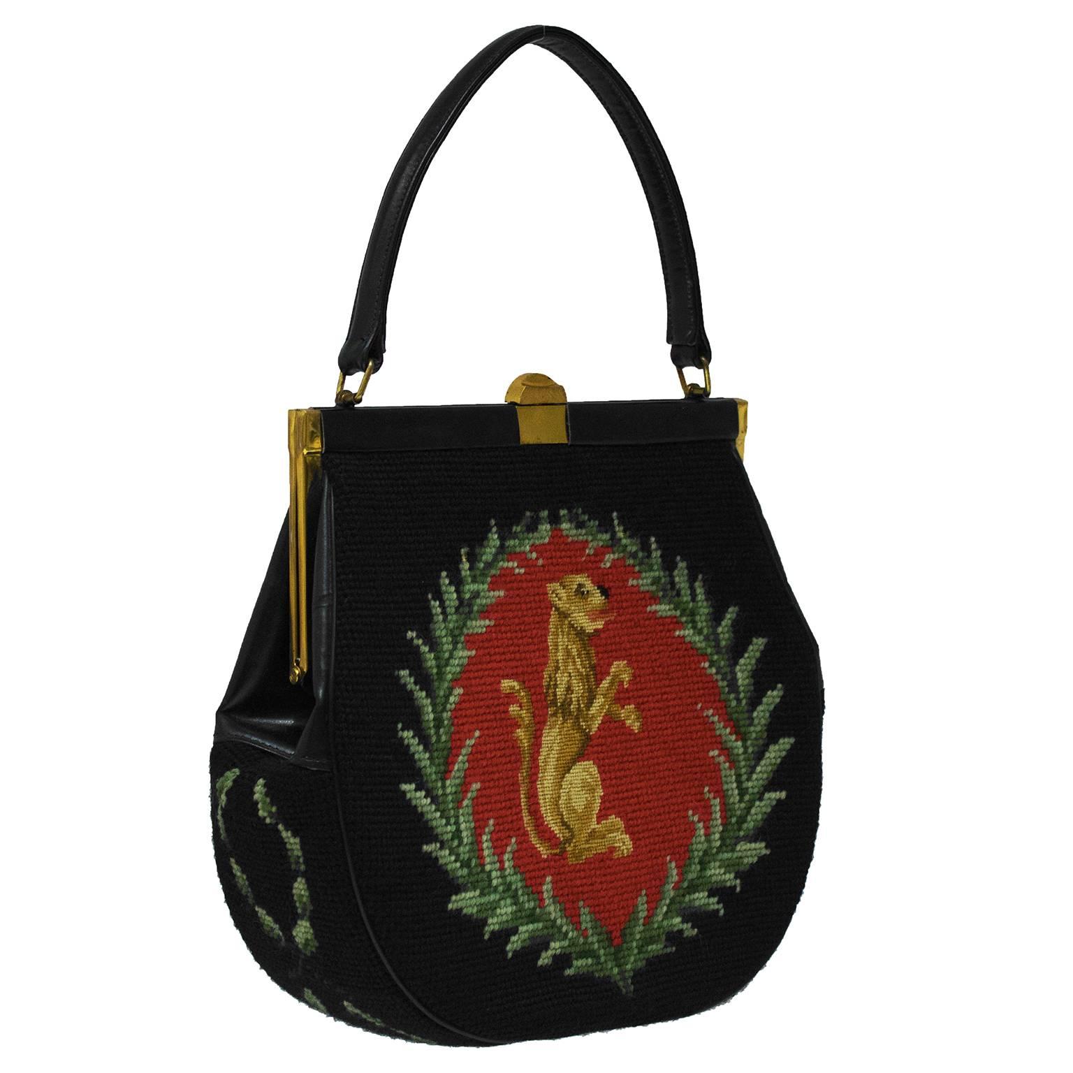 The loveliest of lady bags. Black needlepoint and leather top handle bag from the 1950's. Beautiful all over needle point body with a royal griffen motif surrounded by green branches. Greenery detail on the gusset as well. The rest of the body of