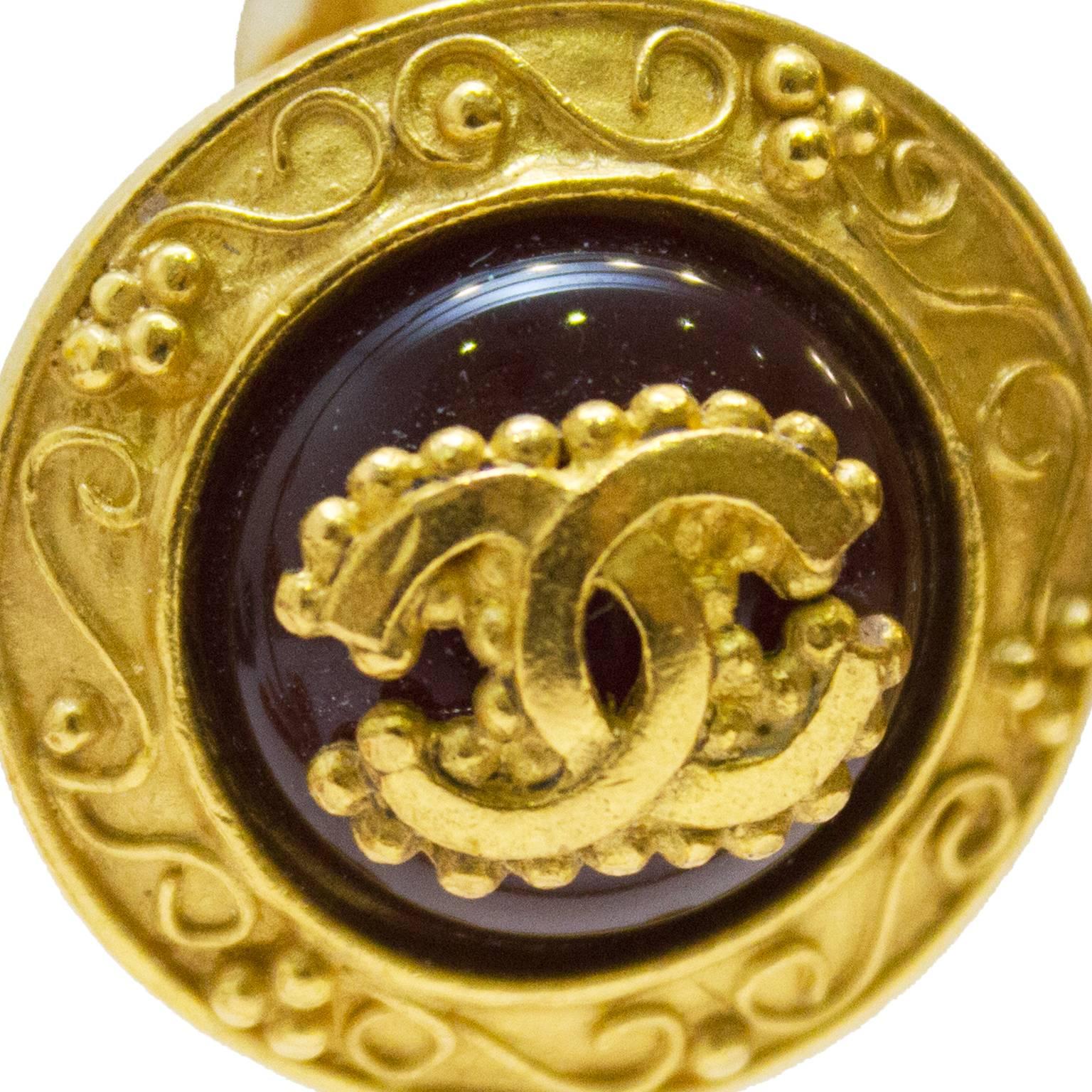 Chanel collection 1996 autumn gold plated and wine colored glass clip on earring. Lovely articulated borders with bead and swirl design. Center glass/resin is deep wine color with mounted CC logo gold plated decorative detail. In excellent