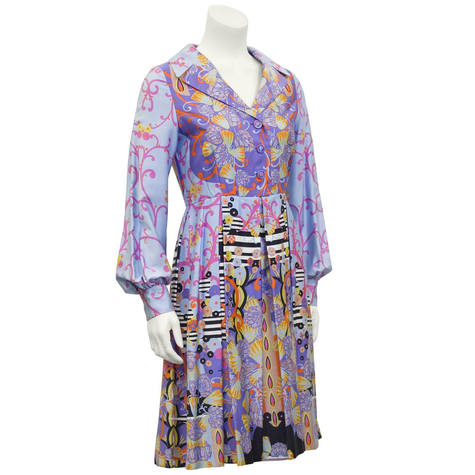 1960's psychedelic print shirt dress featuring stunning shades of purple and lilac with pops of orange and yellow, black and white stripes and seashells. Exaggerated collar with matching buttons and pleated skirt. Luxurious combed cotton fabric,