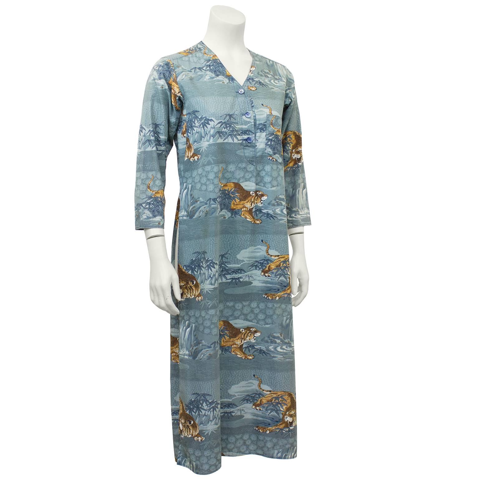 1970's Kenzo JAP blue cotton tunic featuring a Japanese jungle print of waterfalls and the iconic Kenzo tiger. Slits up both legs, 3/4 length sleeves, small pocket on left side of bust when wearing and v-neck with 3 button closure. Very early Kenzo