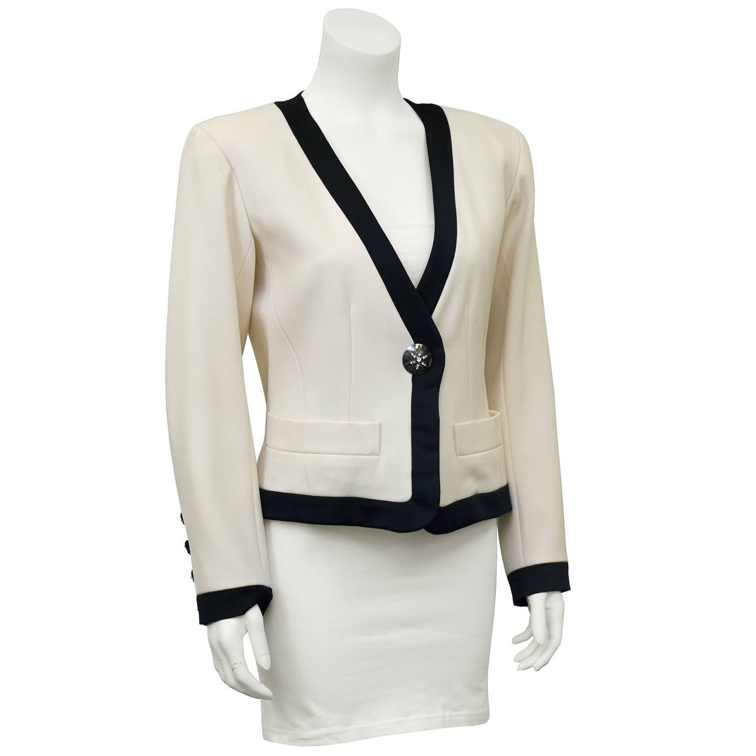 Great 1980's Yves Saint Laurent cropped cream wool gabardine jacket with thick black satin trim. One stunning large sliver button at center embellished with rhinestone star symbol. Five smaller matching buttons at wrists. Deep V front and larger